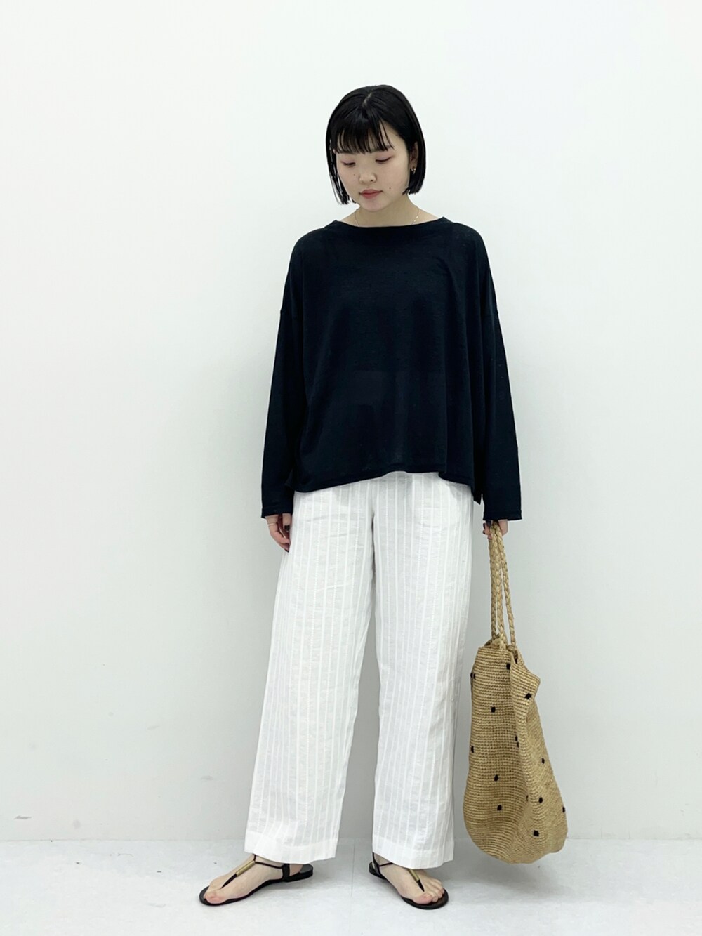 ブラック系のTシャツ/カットソー、ホワイト系のその他パンツ、ベージュ系のバッグを着用したレディースの春コーディネートの2枚目の写真