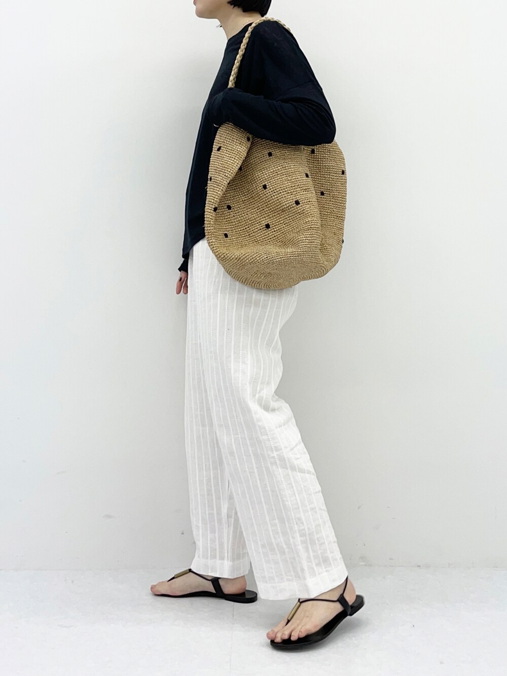 ブラック系のTシャツ/カットソー、ホワイト系のその他パンツ、ベージュ系のバッグを着用したレディースの春コーディネートの5枚目の写真