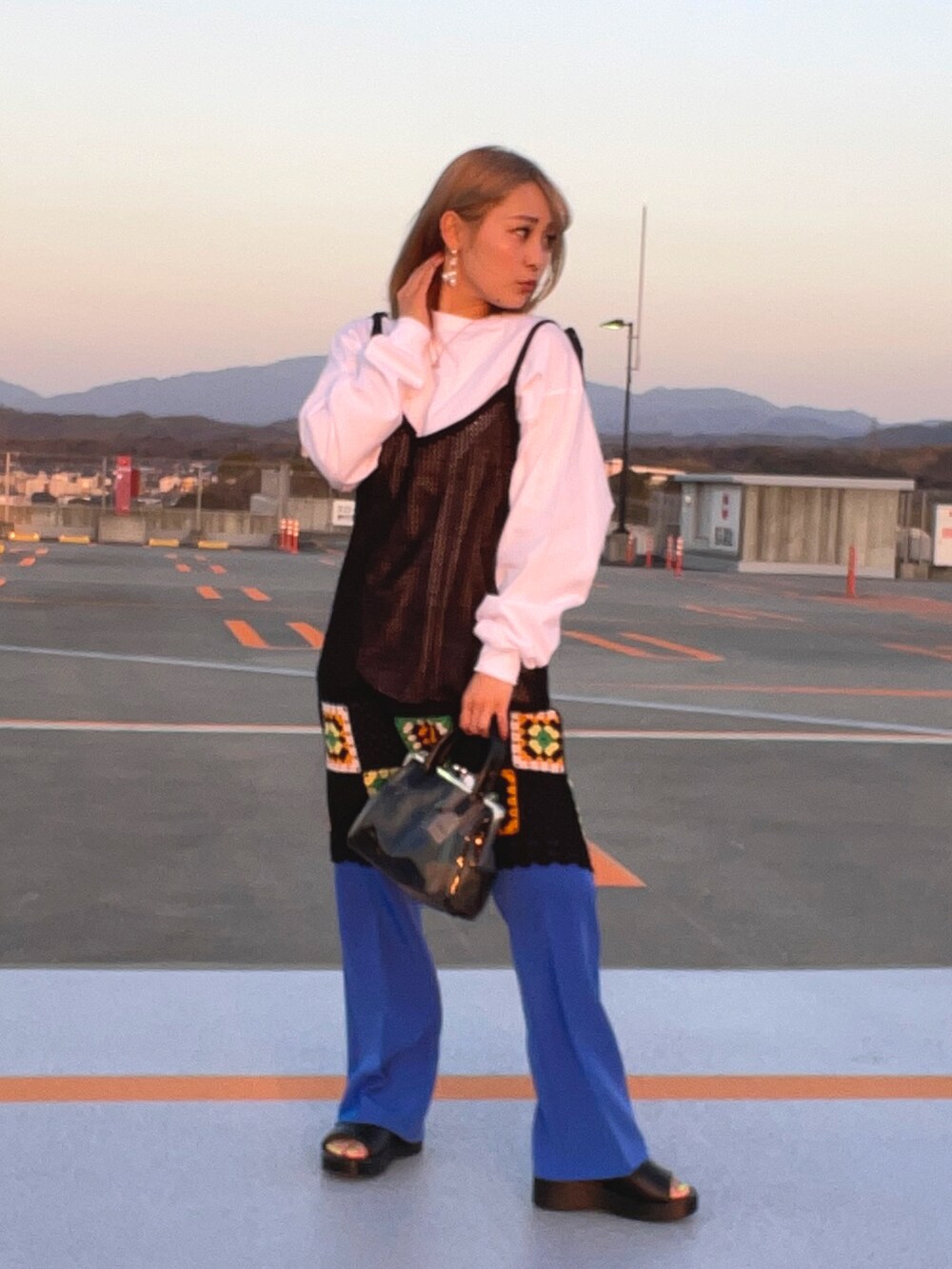 ブラック系のサンダル、ブルー系のスラックス、ブラック系のワンピースを着用したレディースの春コーディネートの2枚目の写真