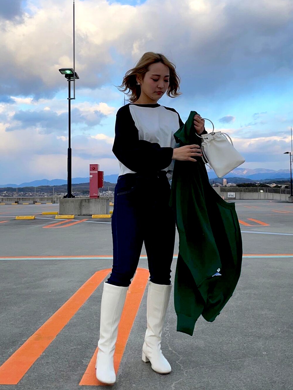 ホワイト系のブーツ、ブルー系のデニムパンツ、ブラック系のカーディガン/ボレロを着用したレディースの冬コーディネートの3枚目の写真