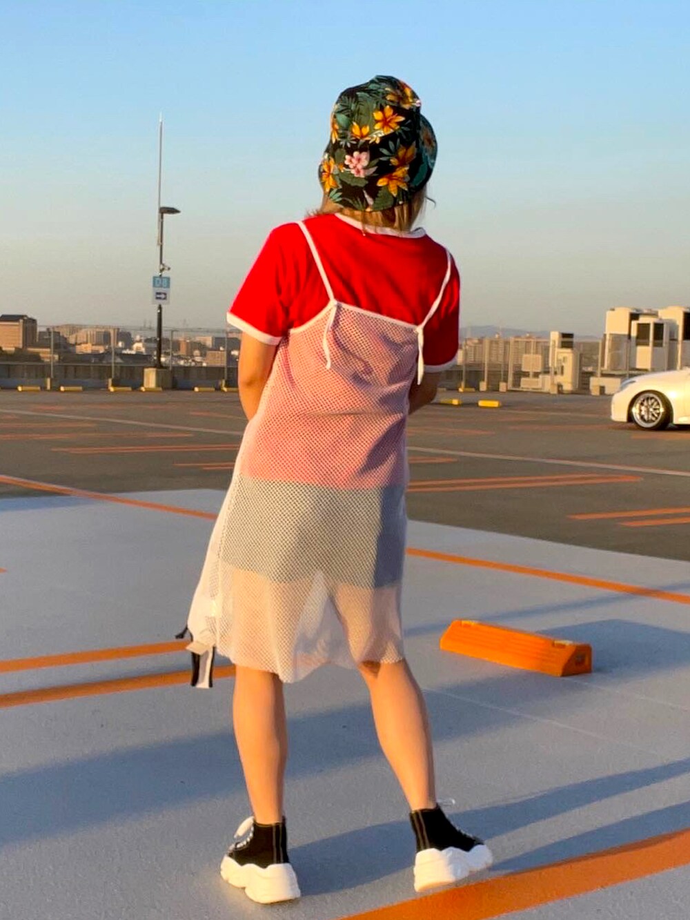 ブラック系のスニーカー、ホワイト系のワンピース、ブルー系のデニムパンツを着用したレディースの春コーディネートの2枚目の写真