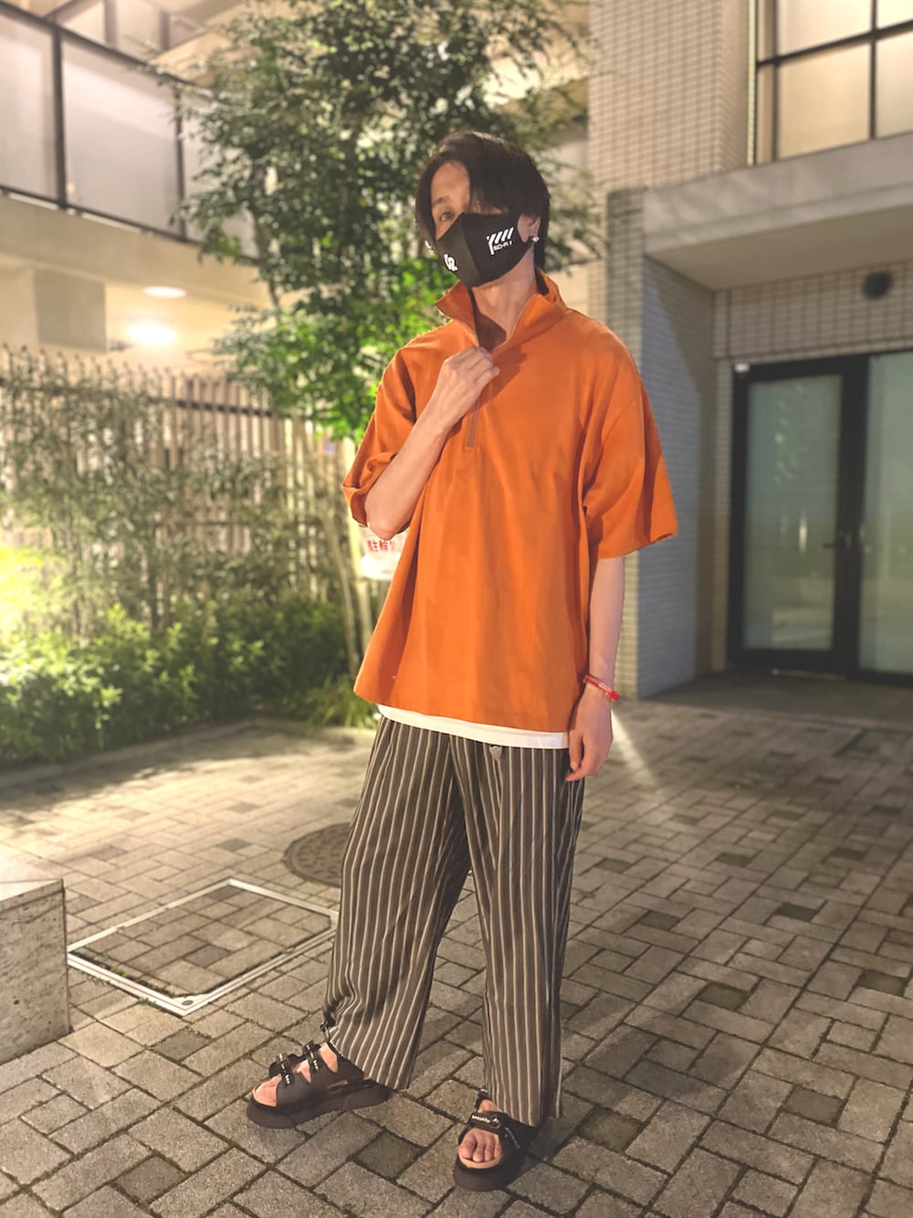 オレンジ系のTシャツ/カットソー、ブラック系のその他パンツ、ブラック系のサンダルを着用したメンズの夏コーディネートの3枚目の写真