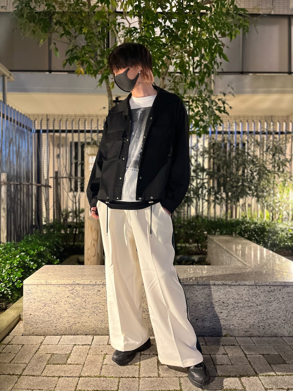 ホワイト系のスラックス、ブラック系のスニーカー、ブラック系のタンクトップを着用したメンズの秋コーディネートの2枚目の写真