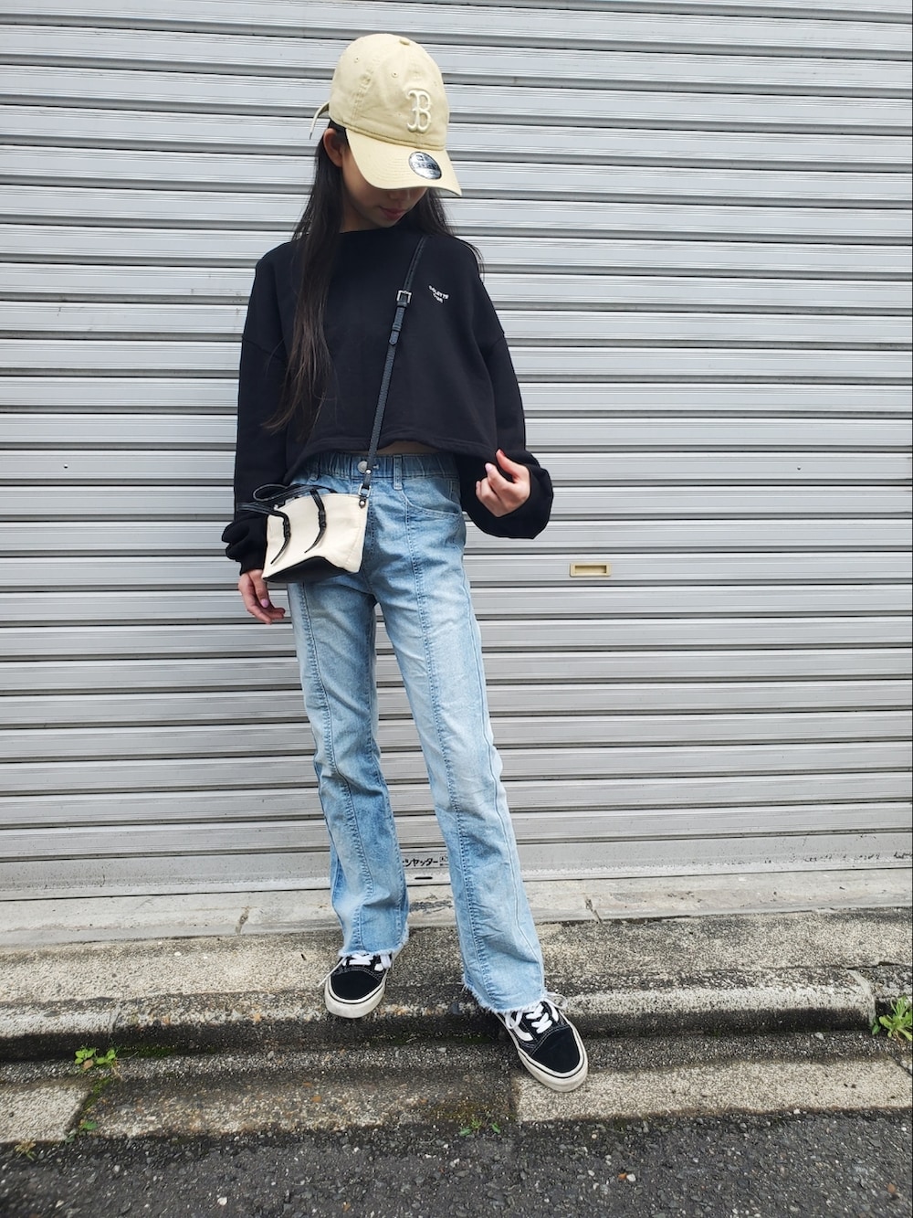 ブラック系のトップス、ブラック系のスニーカー、ホワイト系のショルダーバッグを着用したキッズの春コーディネートの2枚目の写真