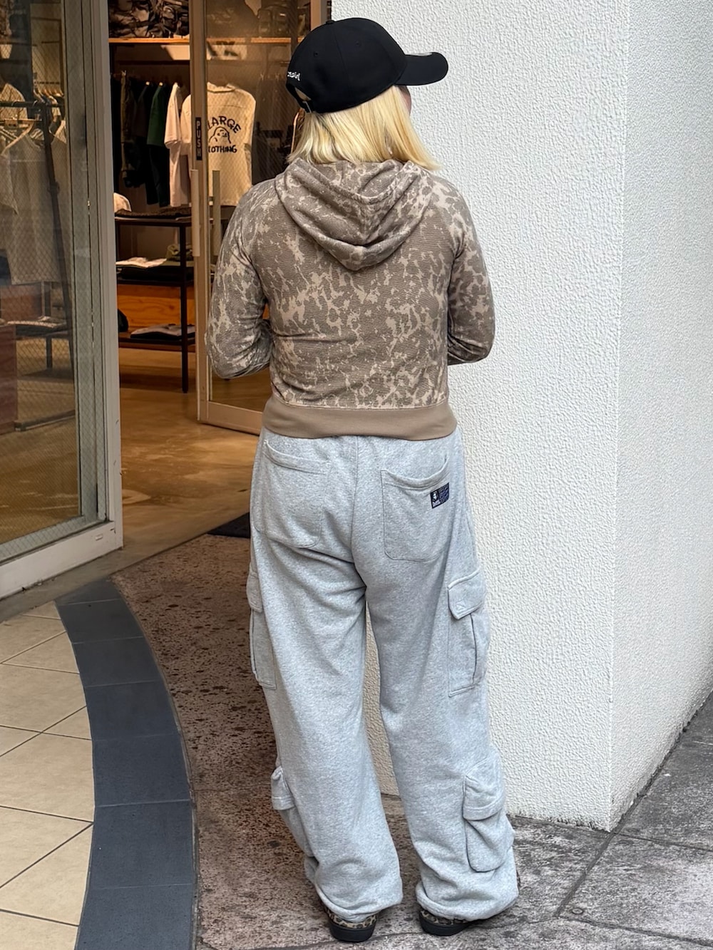 ベージュ系のパーカー、グレー系のスウェットパンツ、ブラック系のキャップを着用したレディースの春コーディネートの2枚目の写真