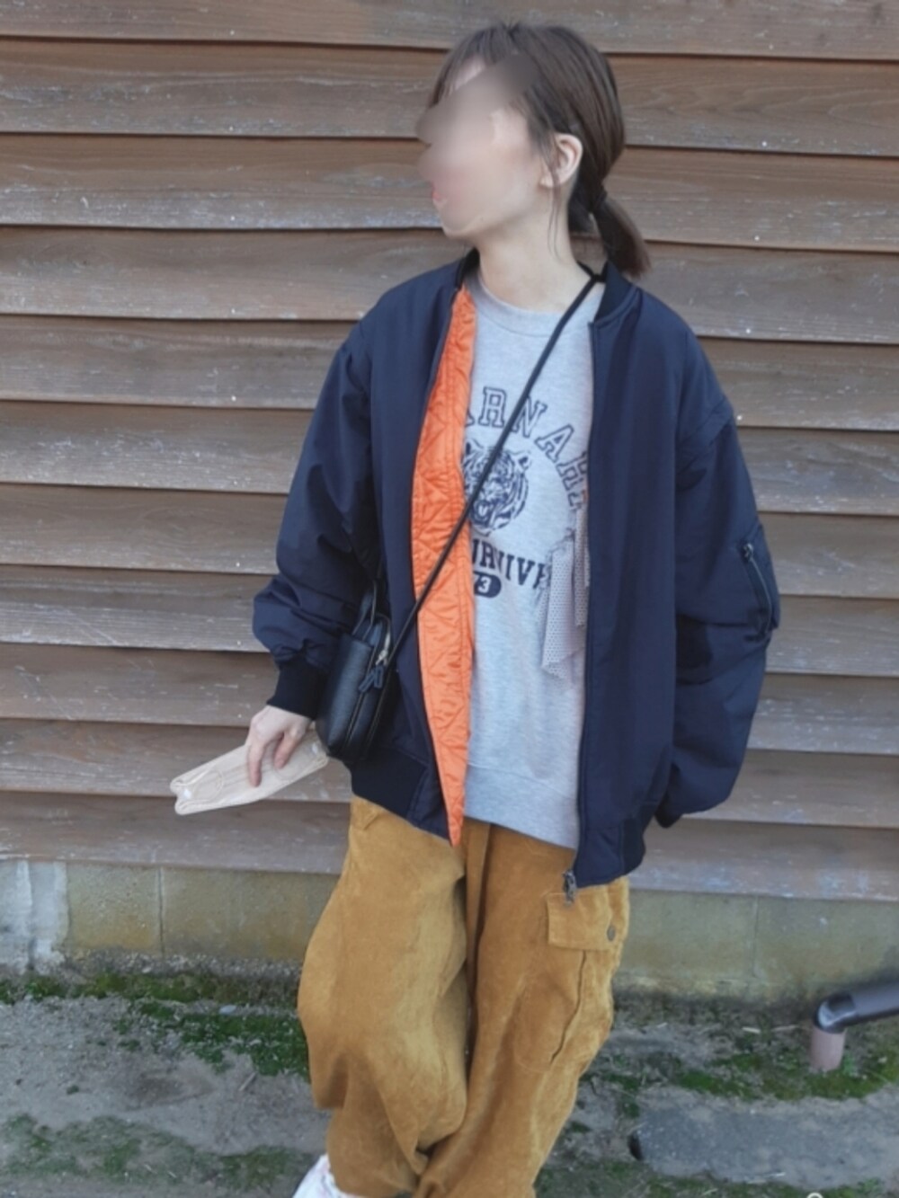 イエロー系のカーゴパンツ、ホワイト系のスニーカー、ブラック系のMA-1を着用したレディースの冬コーディネートの2枚目の写真