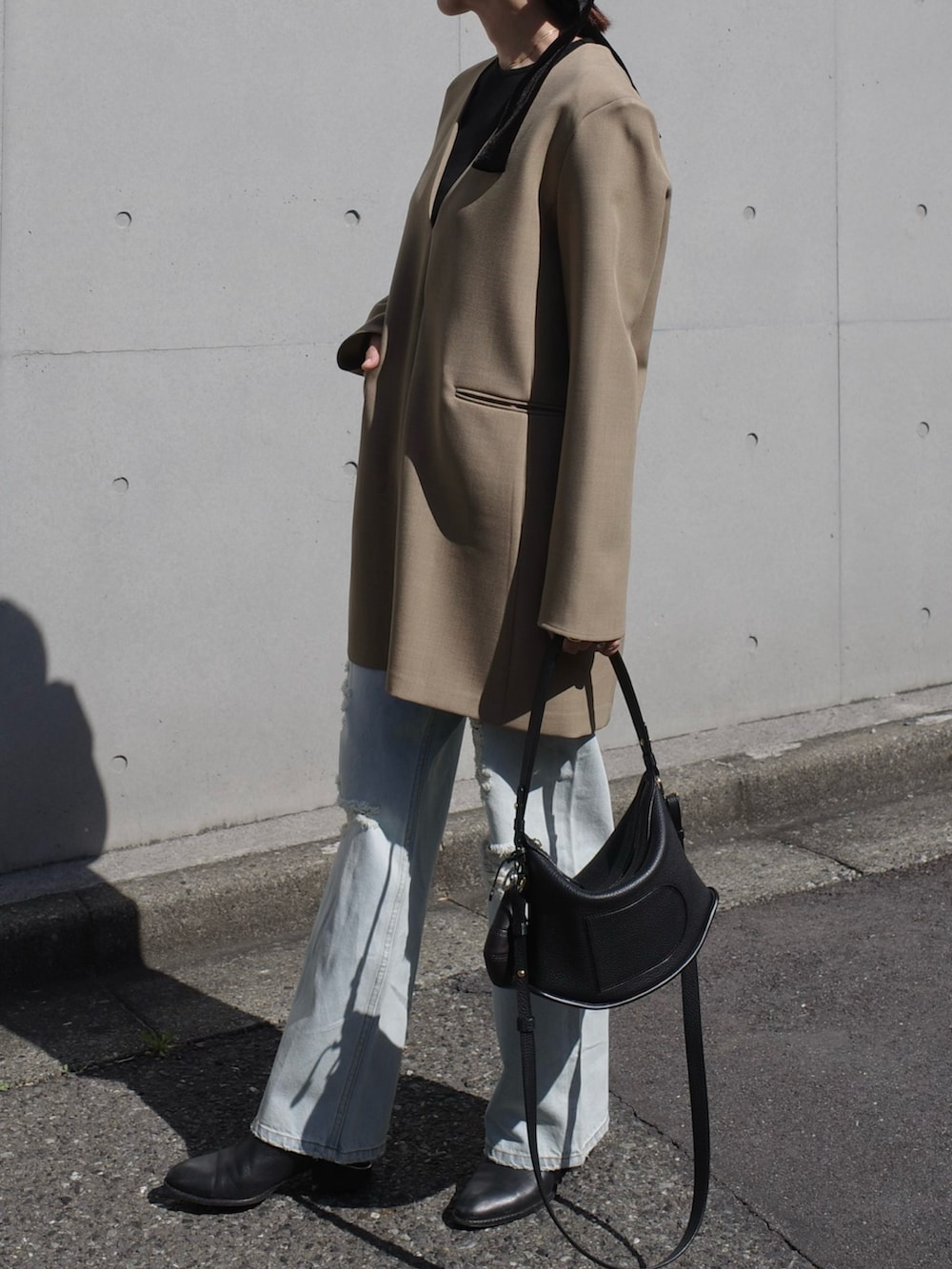 ブラック系のブーツ、ベージュ系のワンピース、ブラック系のバッグを着用したレディースの春コーディネートの2枚目の写真