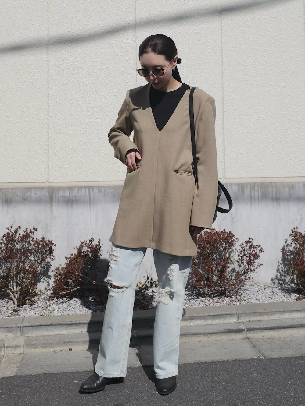 ブラック系のブーツ、ベージュ系のワンピース、ブラック系のバッグを着用したレディースの春コーディネートの3枚目の写真