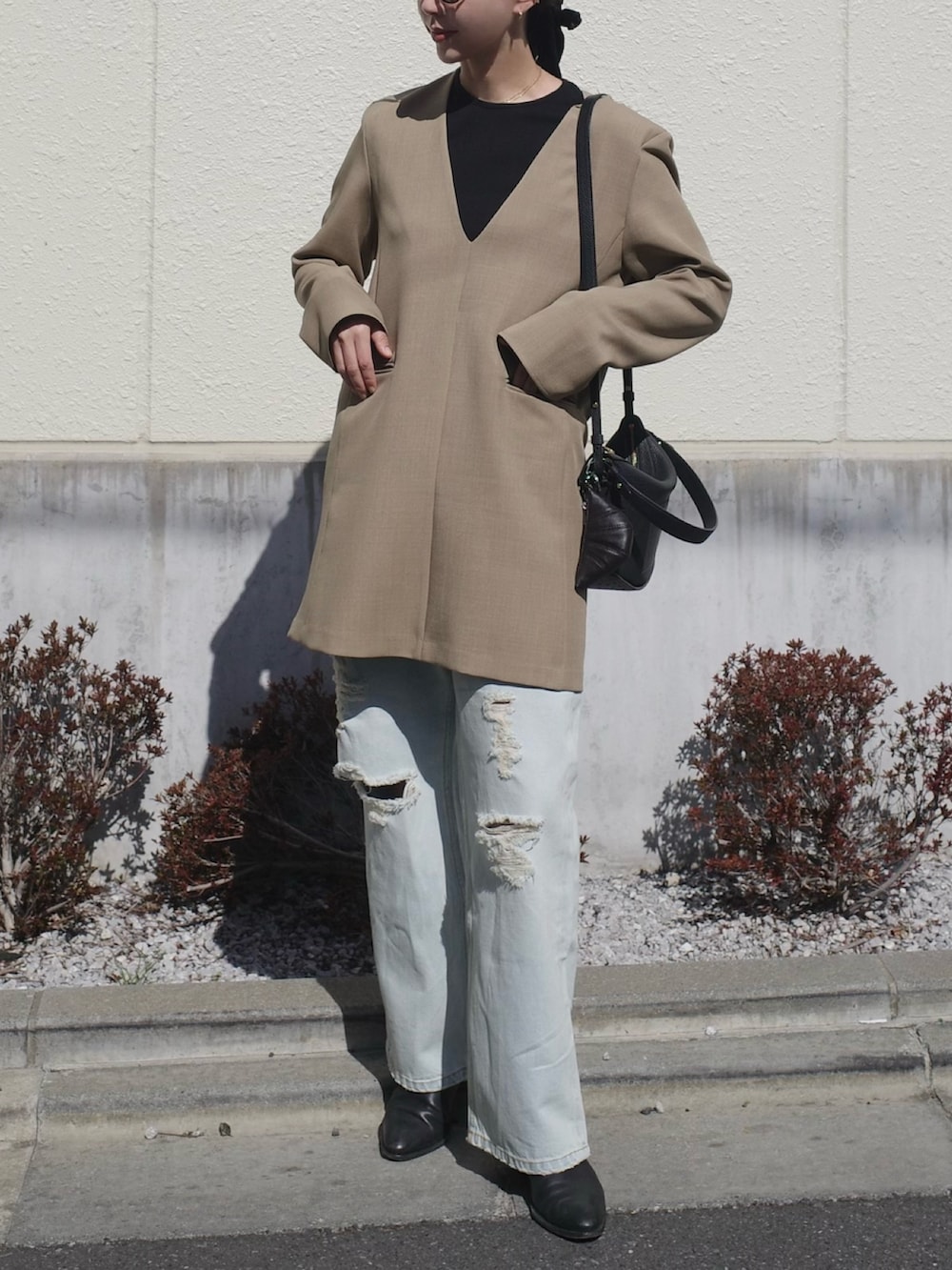 ブラック系のブーツ、ベージュ系のワンピース、ブラック系のバッグを着用したレディースの春コーディネートの4枚目の写真