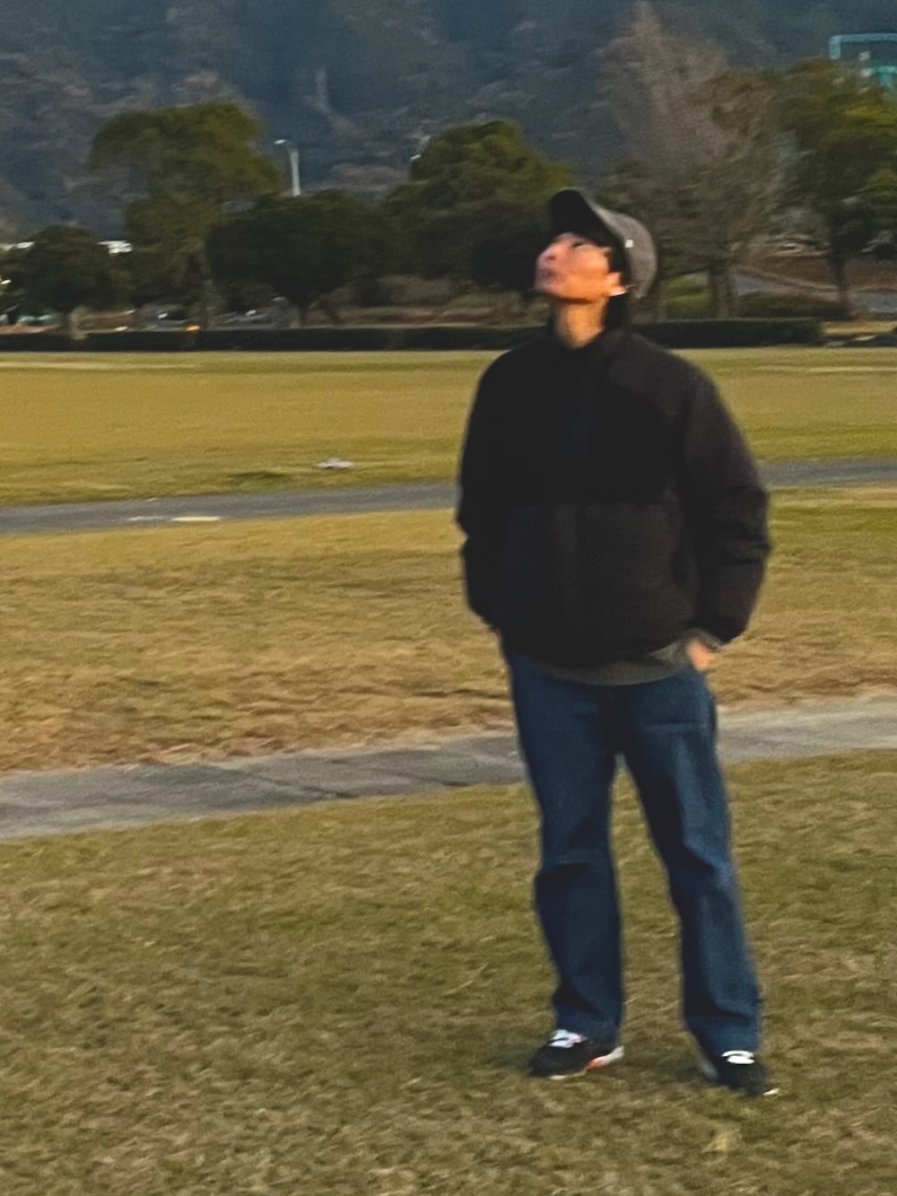 ブラック系のダウンジャケット/コート、ブルー系のデニムパンツ、ブラック系のスニーカーを着用したメンズの春コーディネートの2枚目の写真