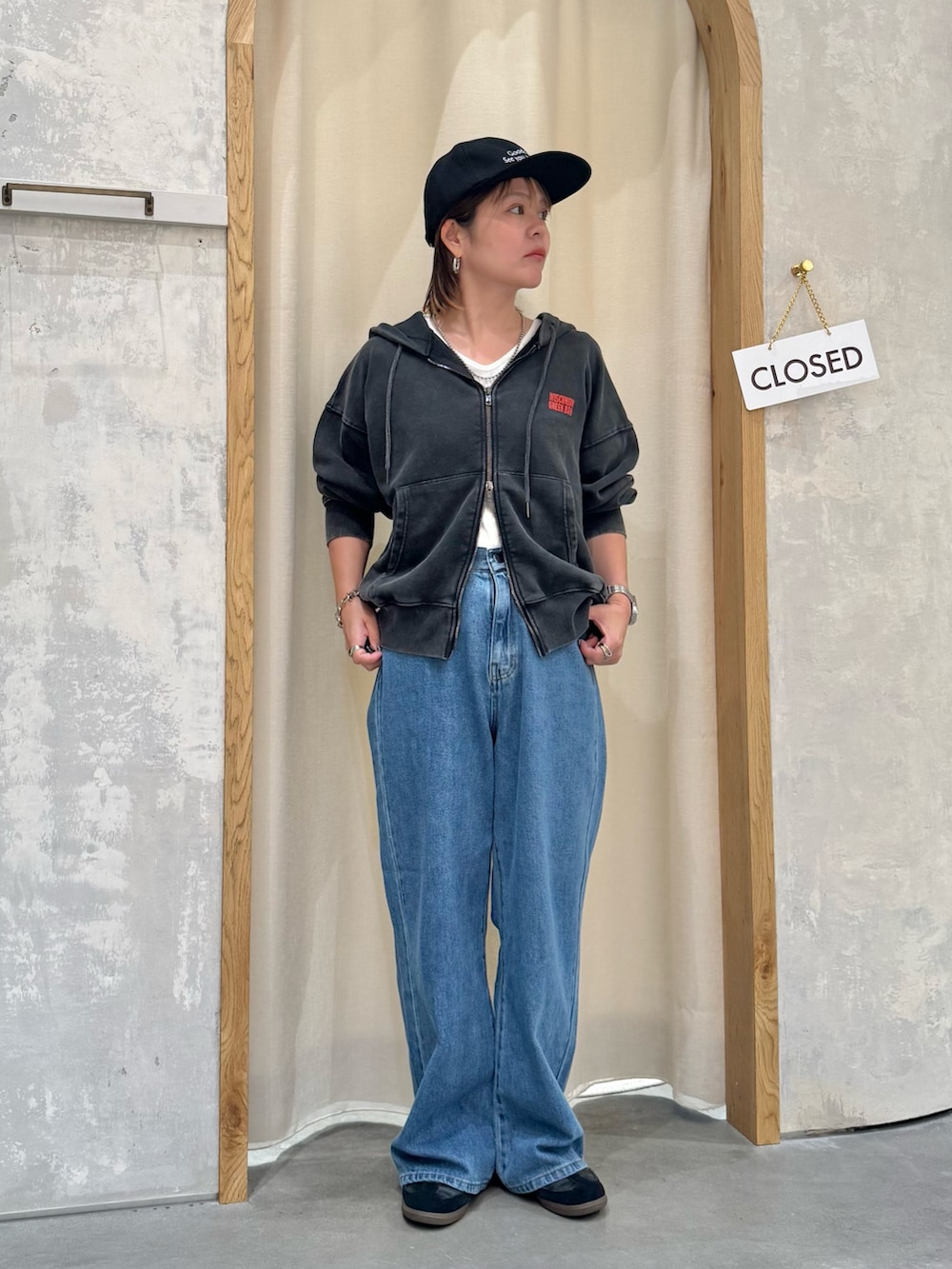 ブルー系のデニムパンツ、ホワイト系のタンクトップ、ブラック系のパーカーを着用したレディースの秋コーディネートの4枚目の写真