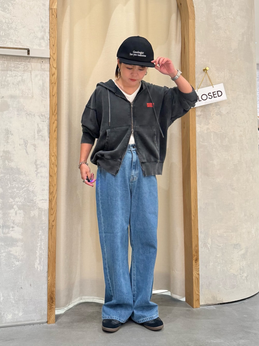 ブルー系のデニムパンツ、ホワイト系のタンクトップ、ブラック系のパーカーを着用したレディースの秋コーディネートの2枚目の写真