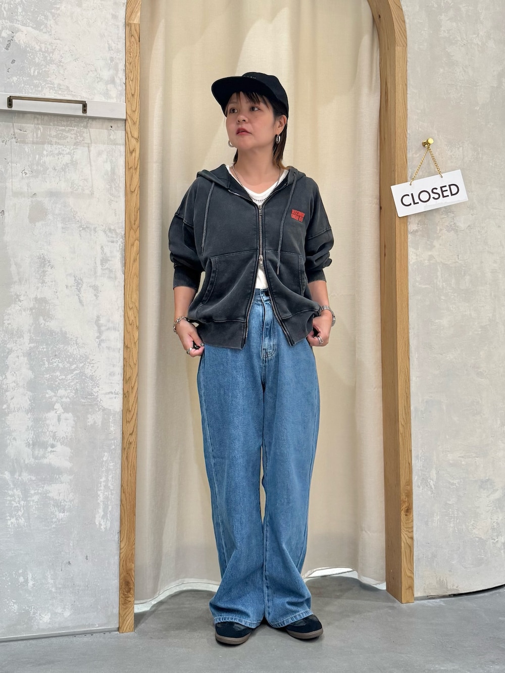 ブルー系のデニムパンツ、ホワイト系のタンクトップ、ブラック系のパーカーを着用したレディースの秋コーディネートの3枚目の写真