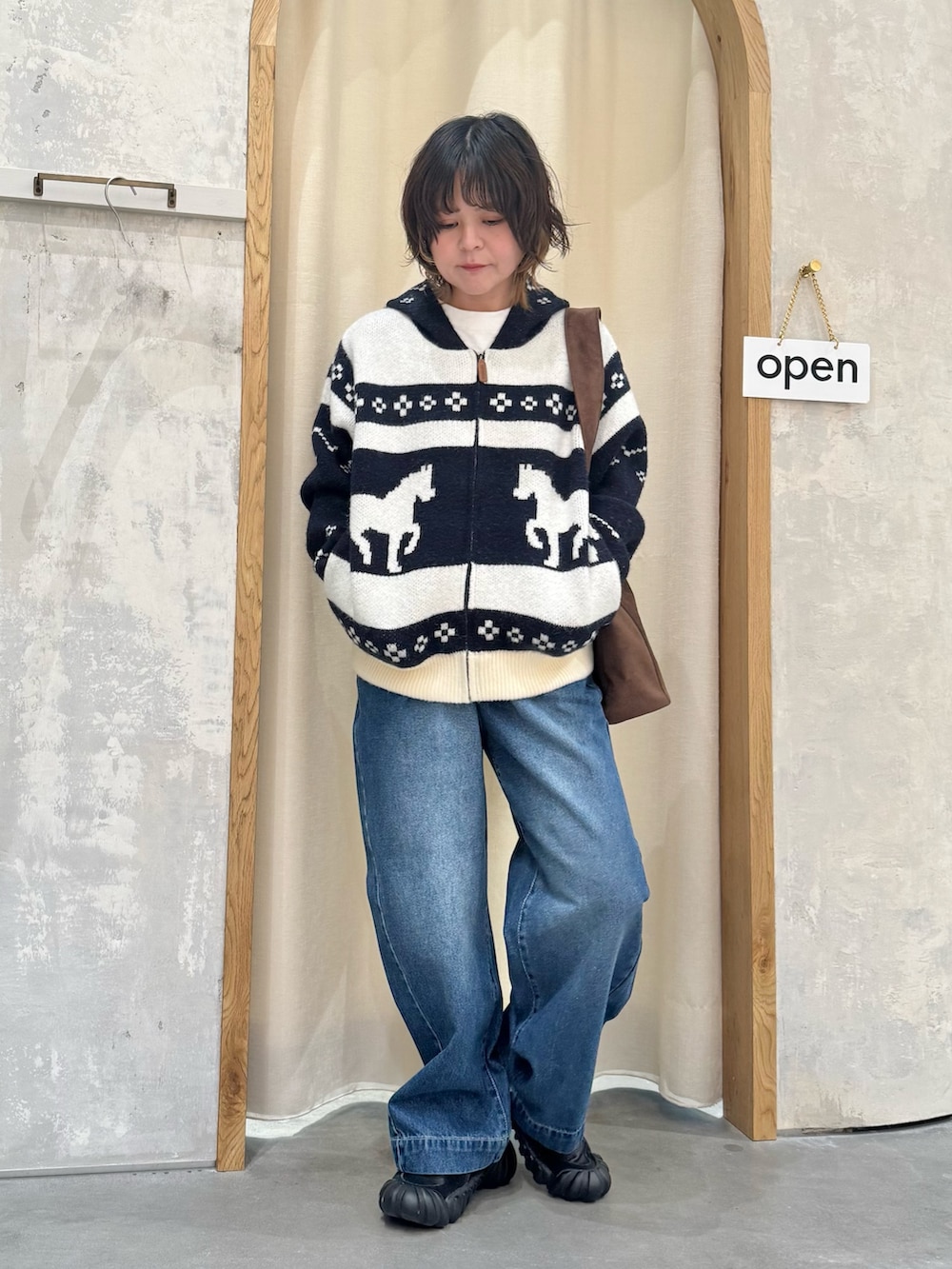 ブルー系のカーディガン/ボレロ、ブルー系のデニムパンツ、ブラウン系のトートバッグを着用したレディースの冬コーディネートの2枚目の写真