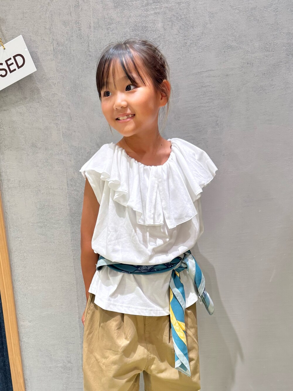 ベージュ系のその他パンツ、ホワイト系のTシャツ/カットソー、グリーン系のバンダナ/スカーフを着用したキッズの秋コーディネートの3枚目の写真