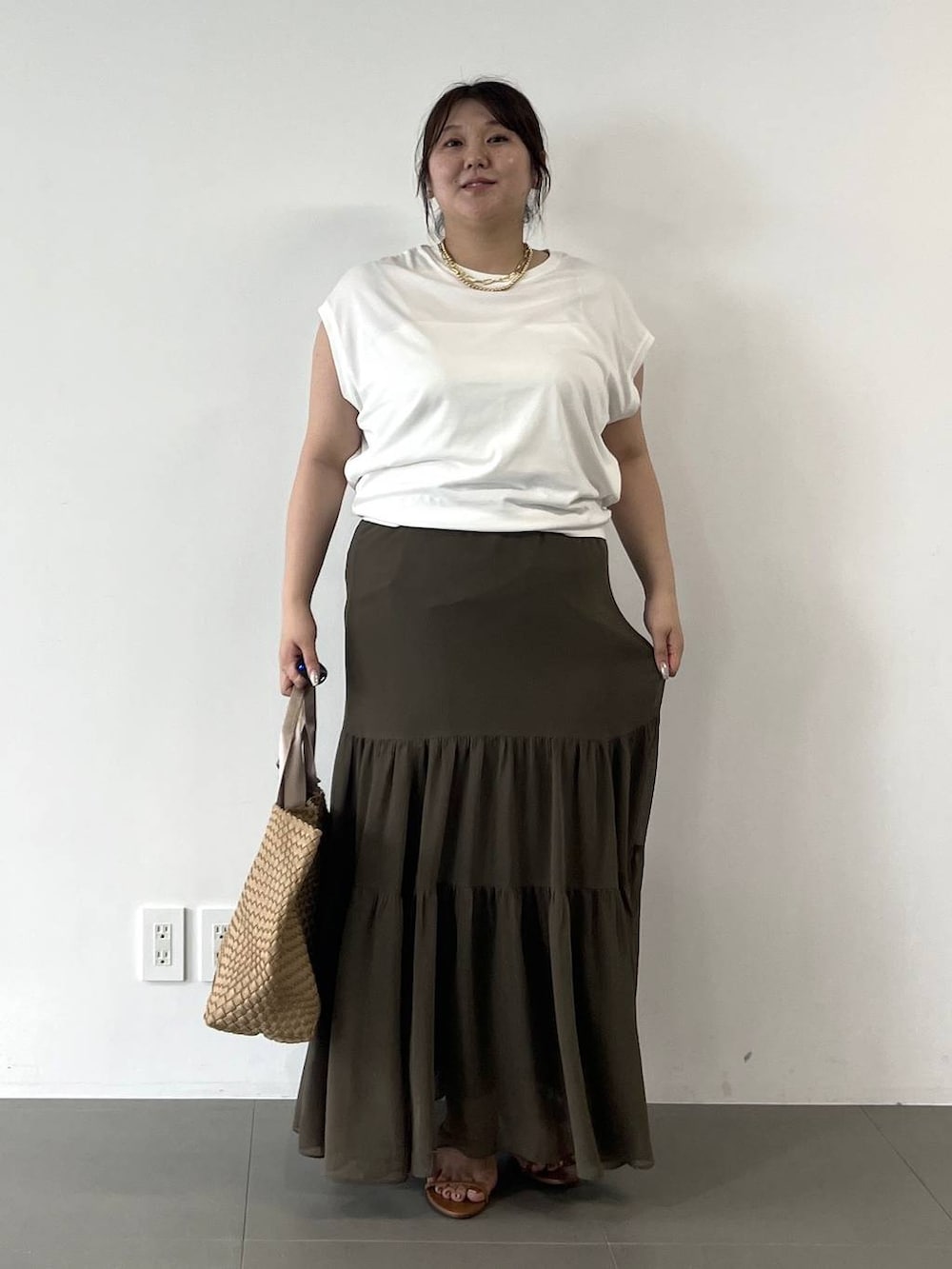 ベージュ系のトートバッグ、グリーン系のスカート、ホワイト系のTシャツ/カットソーを着用したレディースの夏コーディネートの2枚目の写真