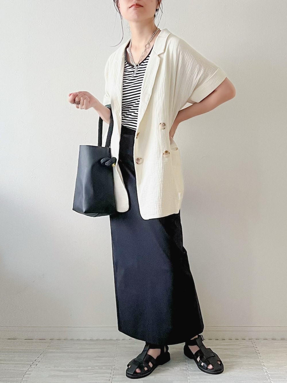 ホワイト系のベスト、ブラック系のボストンバッグ、ブラック系のスカートを着用したレディースの夏コーディネートの3枚目の写真