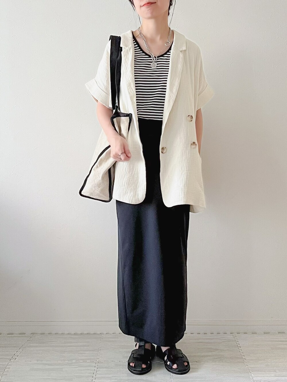 ホワイト系のベスト、ブラック系のボストンバッグ、ブラック系のスカートを着用したレディースの夏コーディネートの4枚目の写真