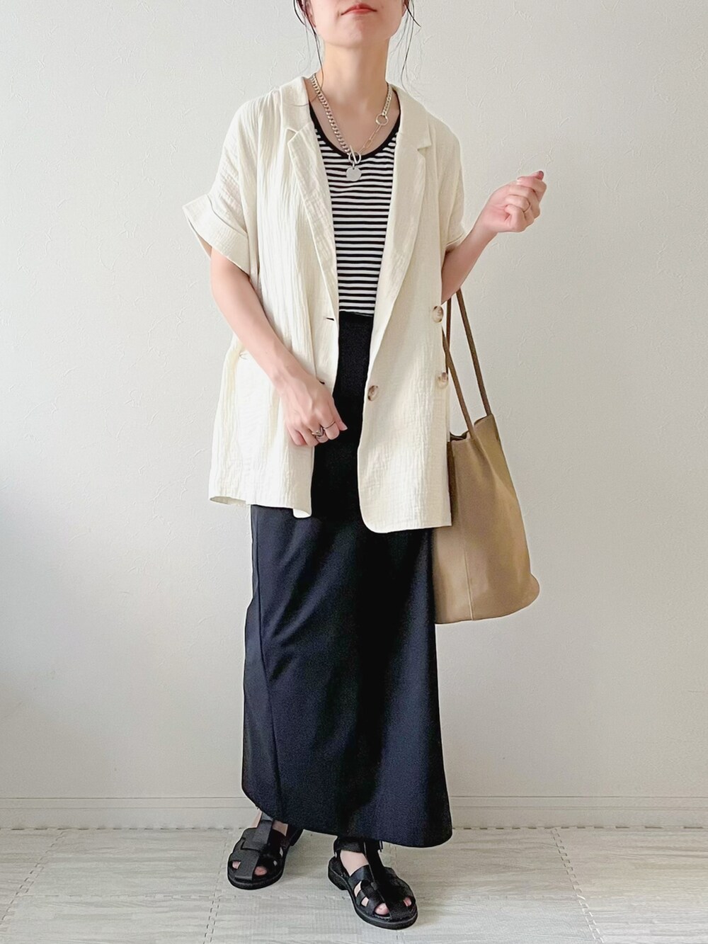 ホワイト系のベスト、ブラック系のボストンバッグ、ブラック系のスカートを着用したレディースの夏コーディネートの2枚目の写真