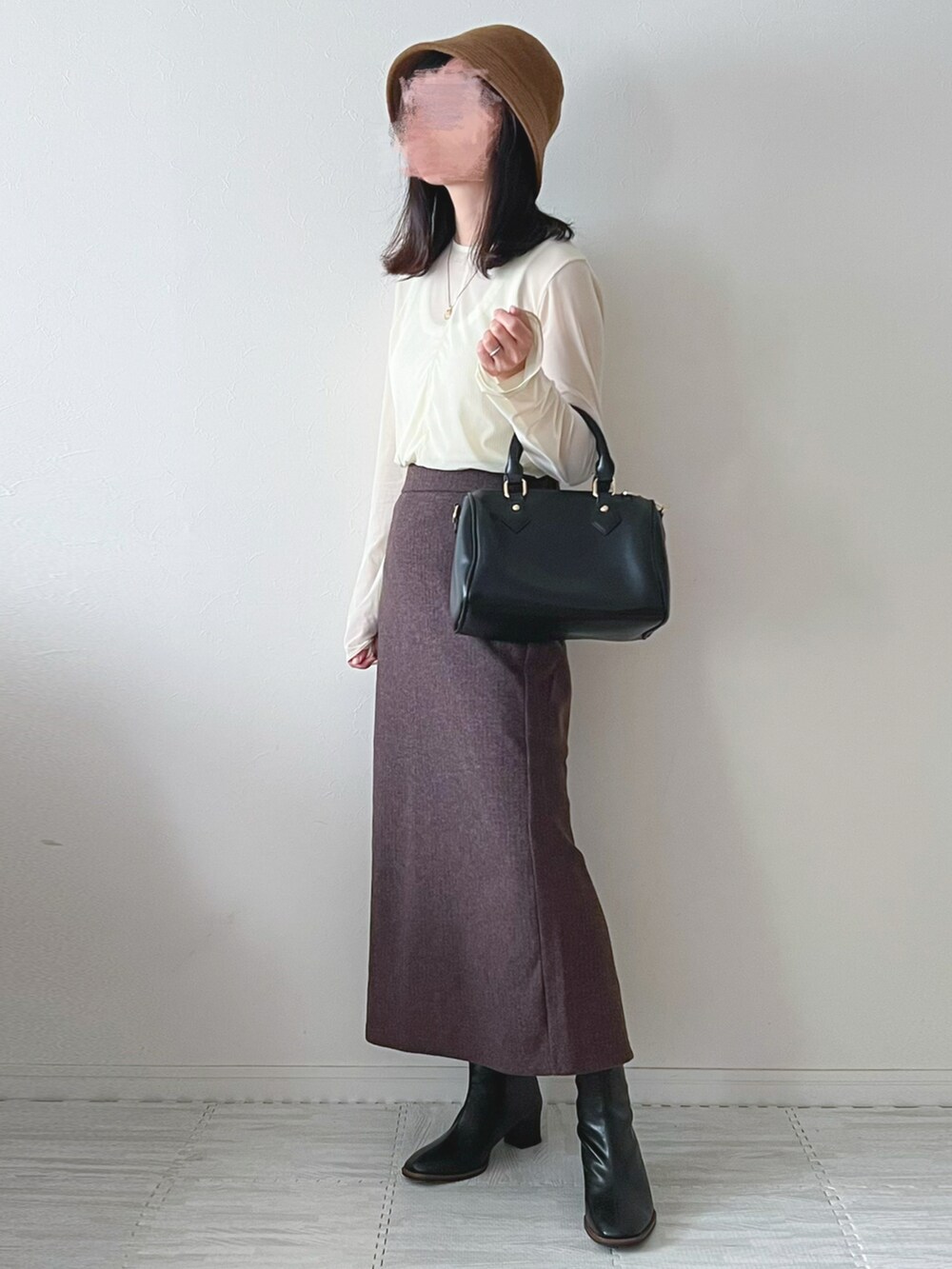 ブラック系のボストンバッグ、ブラック系のブーツ、ブラウン系のスカートを着用したレディースの秋コーディネートの2枚目の写真