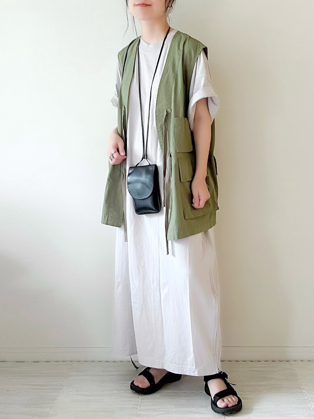グリーン系のベスト、ブラック系のショルダーバッグ、グレー系のワンピースを着用したレディースの夏コーディネートの2枚目の写真