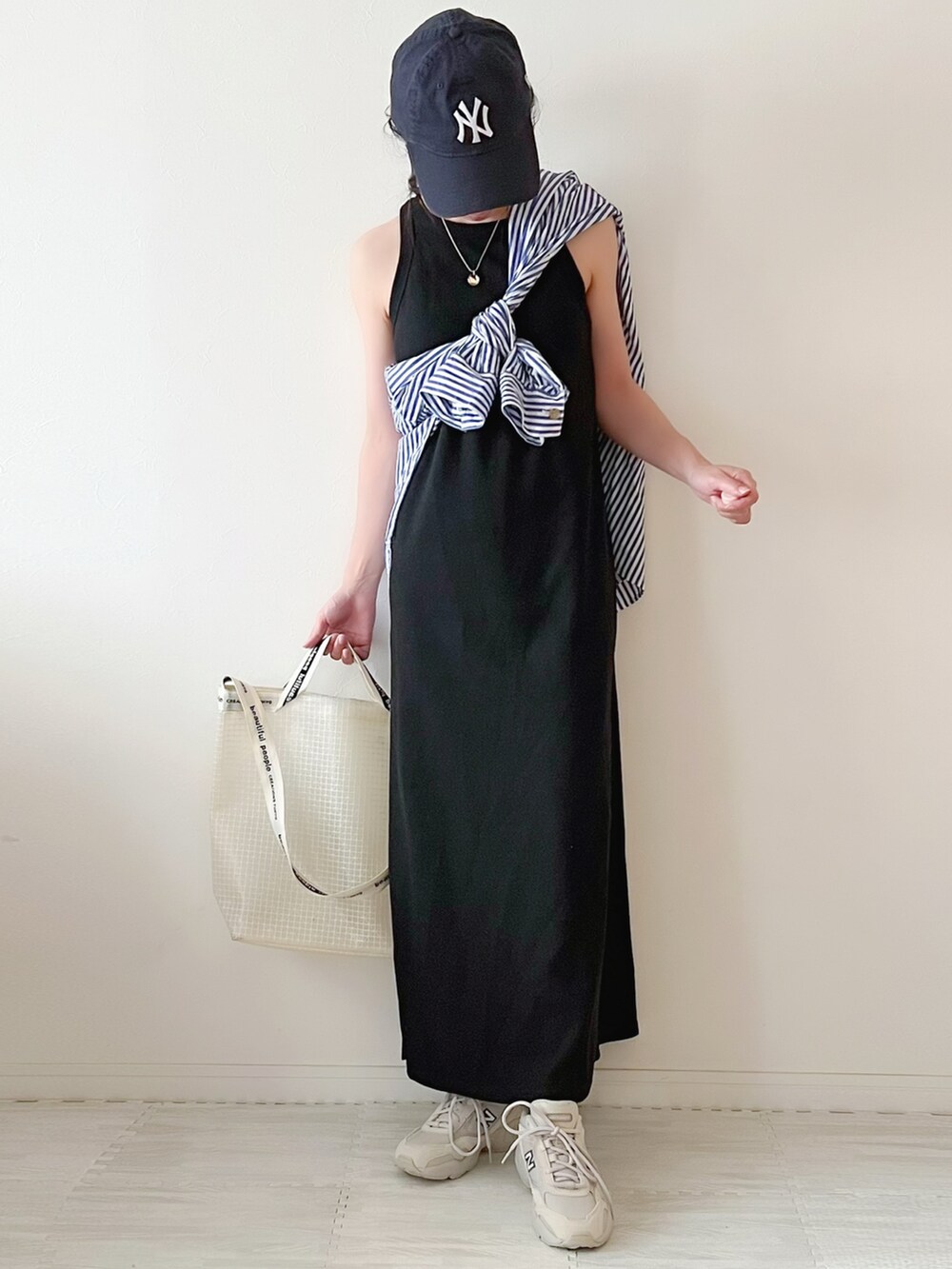 ベージュ系のスニーカー、ホワイト系のショルダーバッグ、ブラック系のワンピースを着用したレディースの夏コーディネートの3枚目の写真