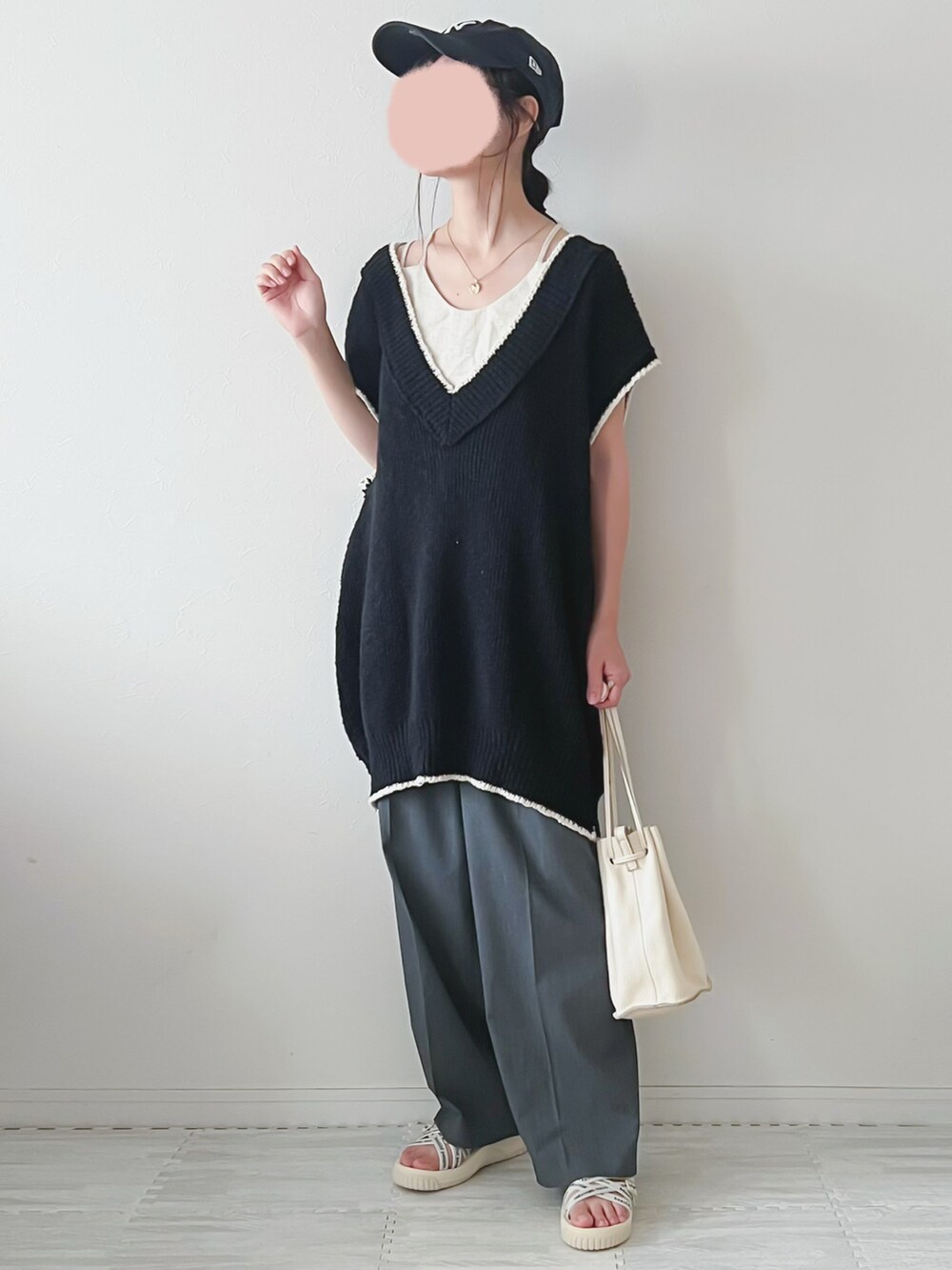 ブラック系のベスト、ベージュ系のショルダーバッグ、グレー系のパンツを着用したレディースの夏コーディネートの3枚目の写真