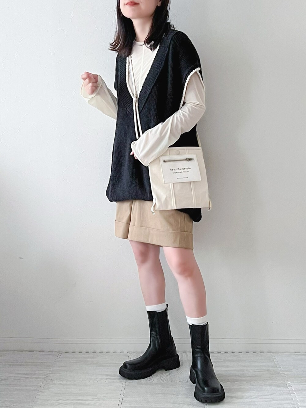 ブラック系のベスト、ブラック系のブーツ、ブラック系のボストンバッグを着用したレディースの秋コーディネートの3枚目の写真