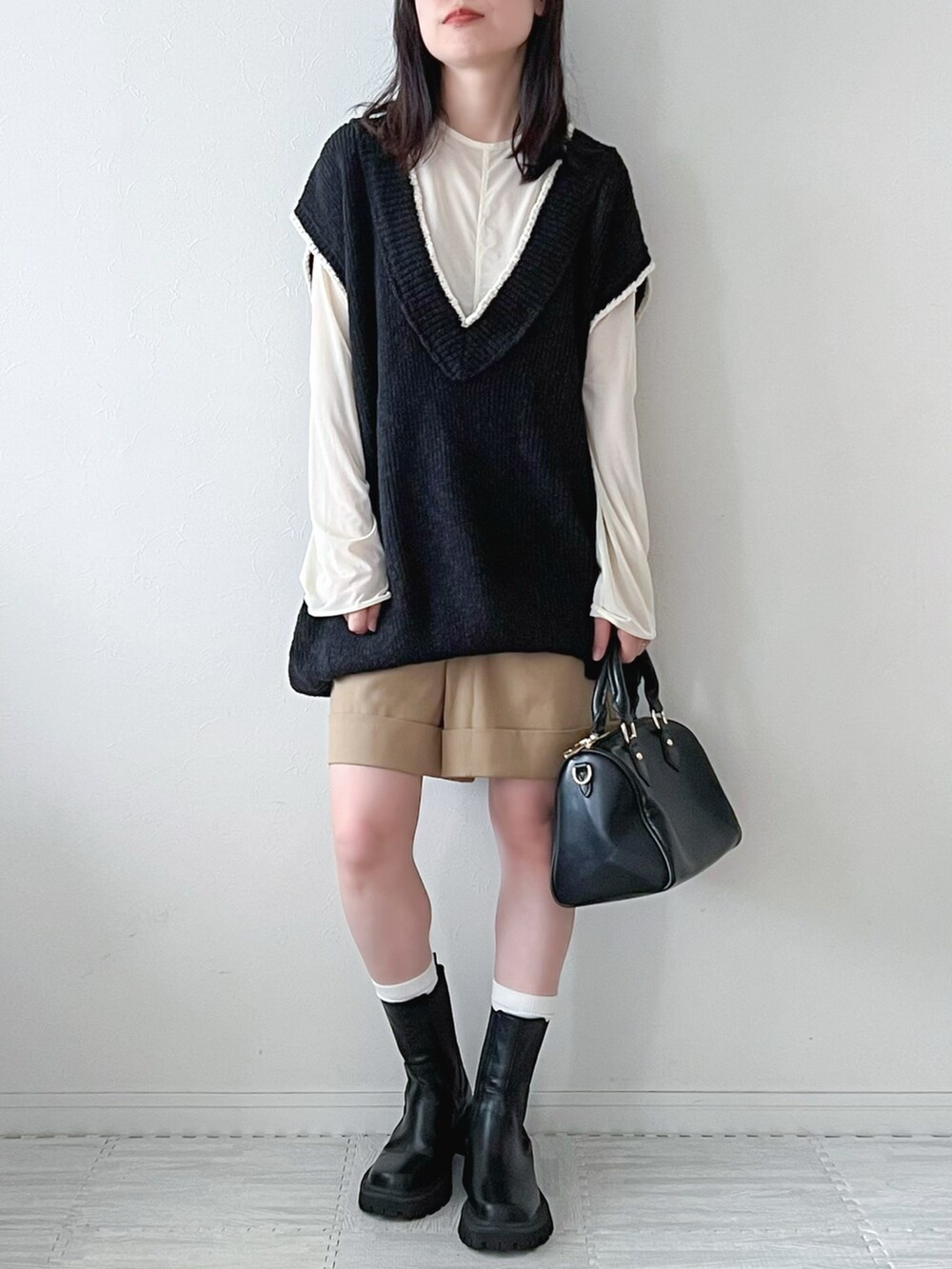 ブラック系のベスト、ブラック系のブーツ、ブラック系のボストンバッグを着用したレディースの秋コーディネートの2枚目の写真