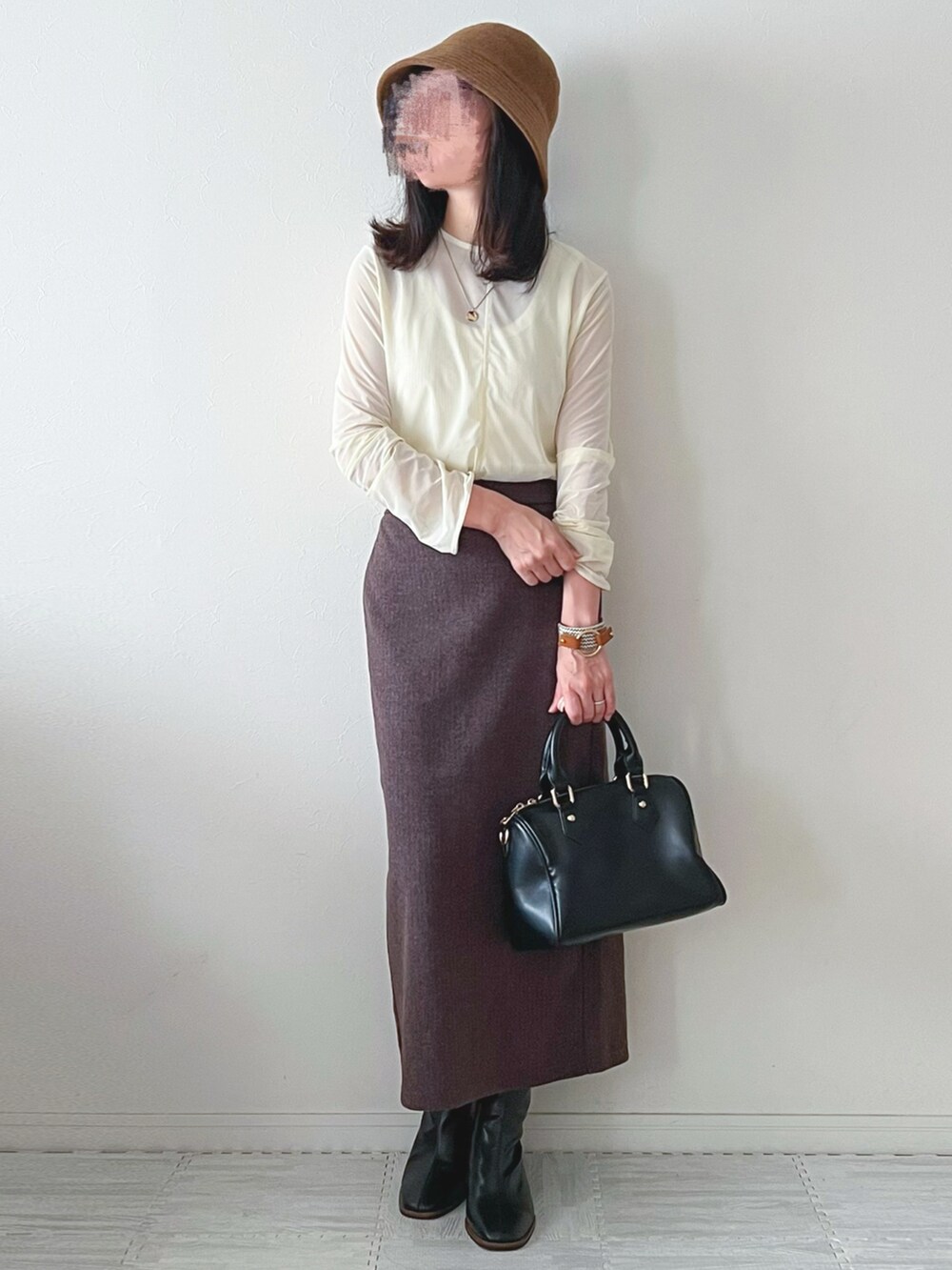 ブラック系のボストンバッグ、ブラック系のブーツ、ブラウン系のスカートを着用したレディースの秋コーディネートの3枚目の写真