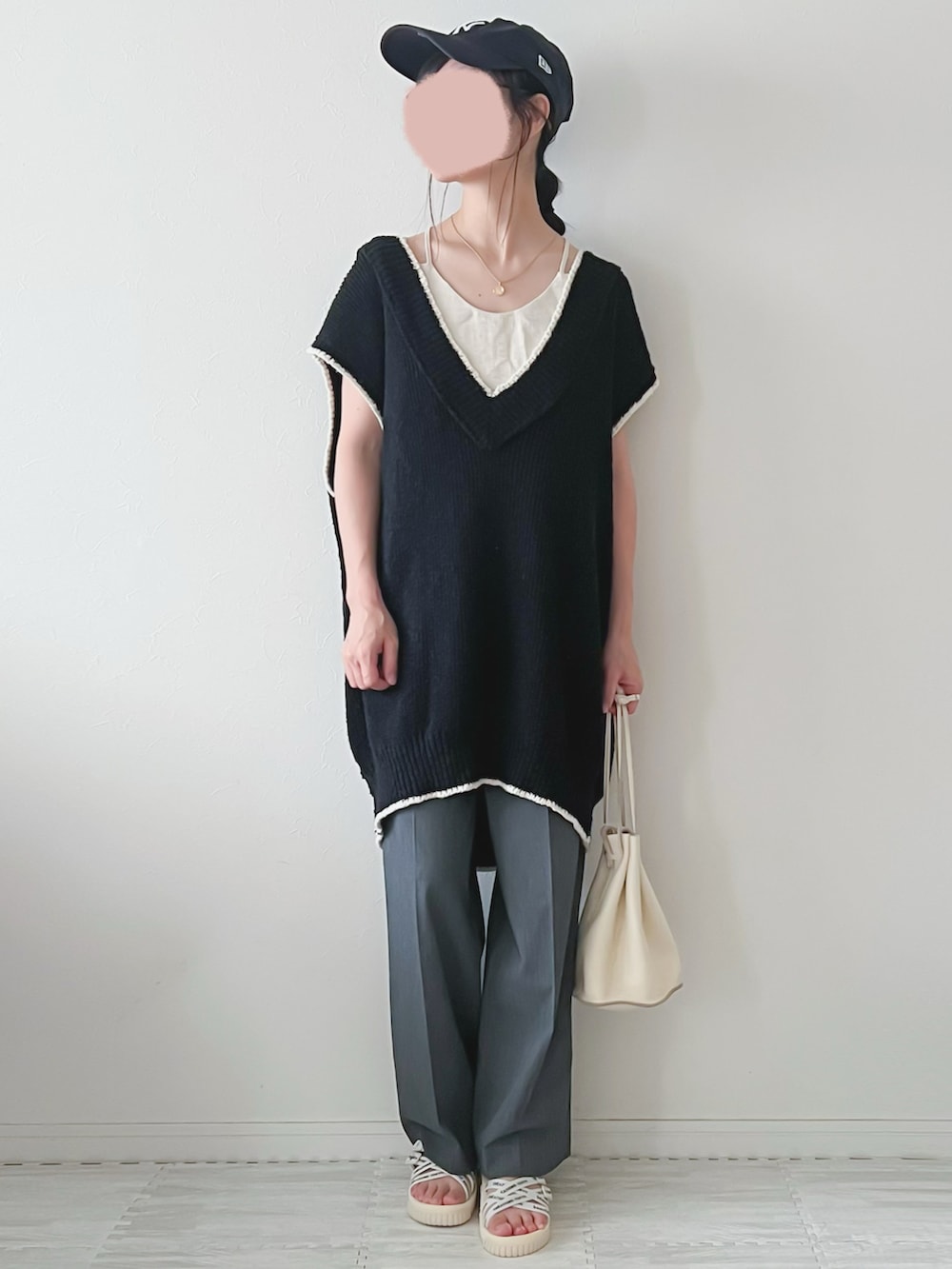 ブラック系のベスト、ベージュ系のショルダーバッグ、グレー系のパンツを着用したレディースの夏コーディネートの2枚目の写真