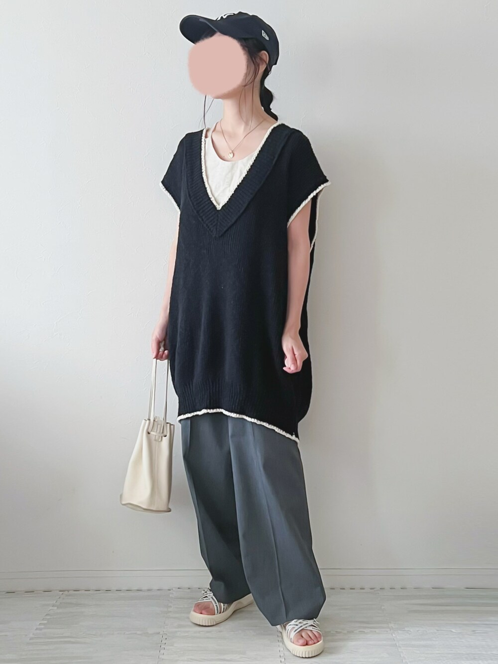 ブラック系のベスト、ベージュ系のショルダーバッグ、グレー系のパンツを着用したレディースの夏コーディネートの4枚目の写真