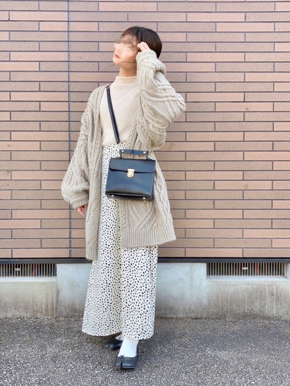 ベージュ系のカーディガン/ボレロ、ブラック系のショルダーバッグ、ホワイト系のニット/セーターを着用したレディースの冬コーディネートの3枚目の写真
