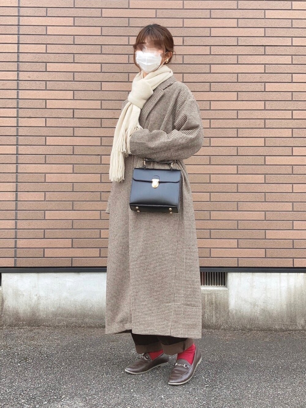 ブラック系のショルダーバッグ、ブラウン系のトレンチコート、ブラウン系のローファーを着用したレディースの冬コーディネートの2枚目の写真