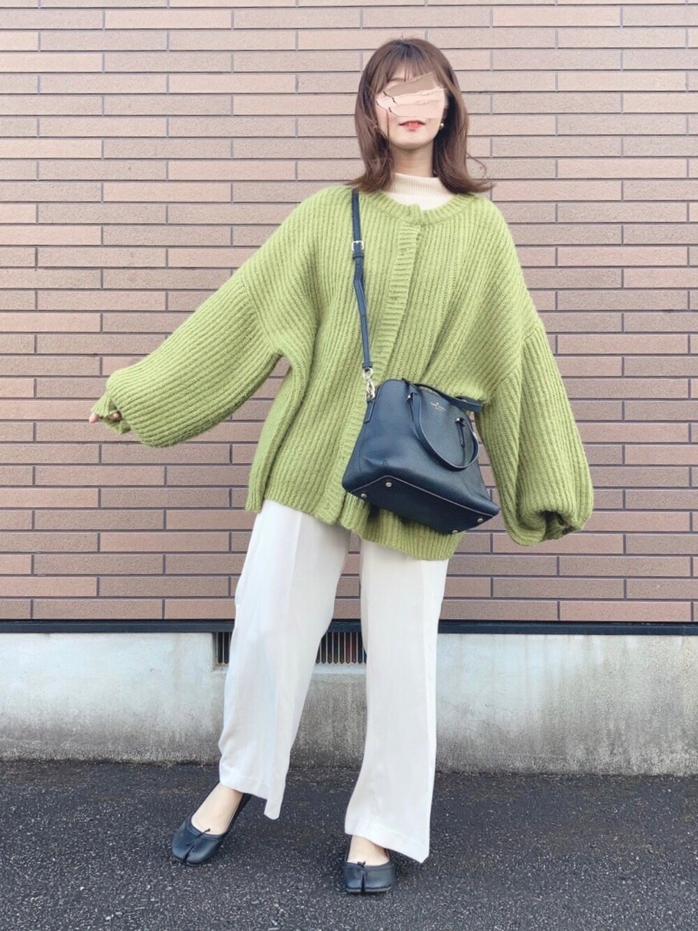 グリーン系のカーディガン/ボレロ、ブラック系のハンドバッグ、ホワイト系のニット/セーターを着用したレディースの冬コーディネートの2枚目の写真