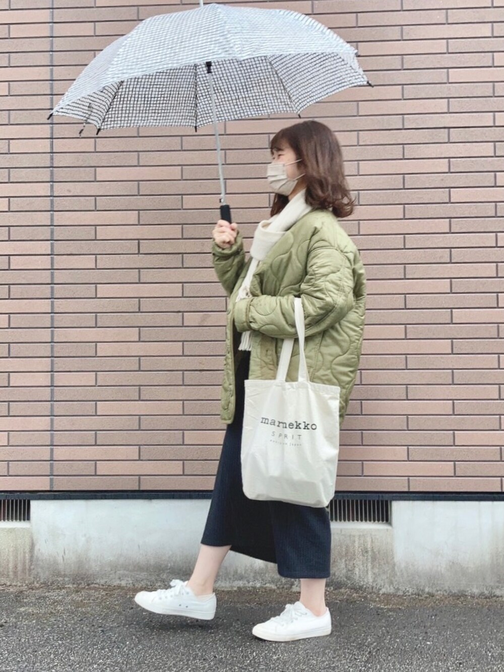 グリーン系のジャケット/アウター、ホワイト系のトートバッグ、ホワイト系のスニーカーを着用したレディースの冬コーディネートの2枚目の写真