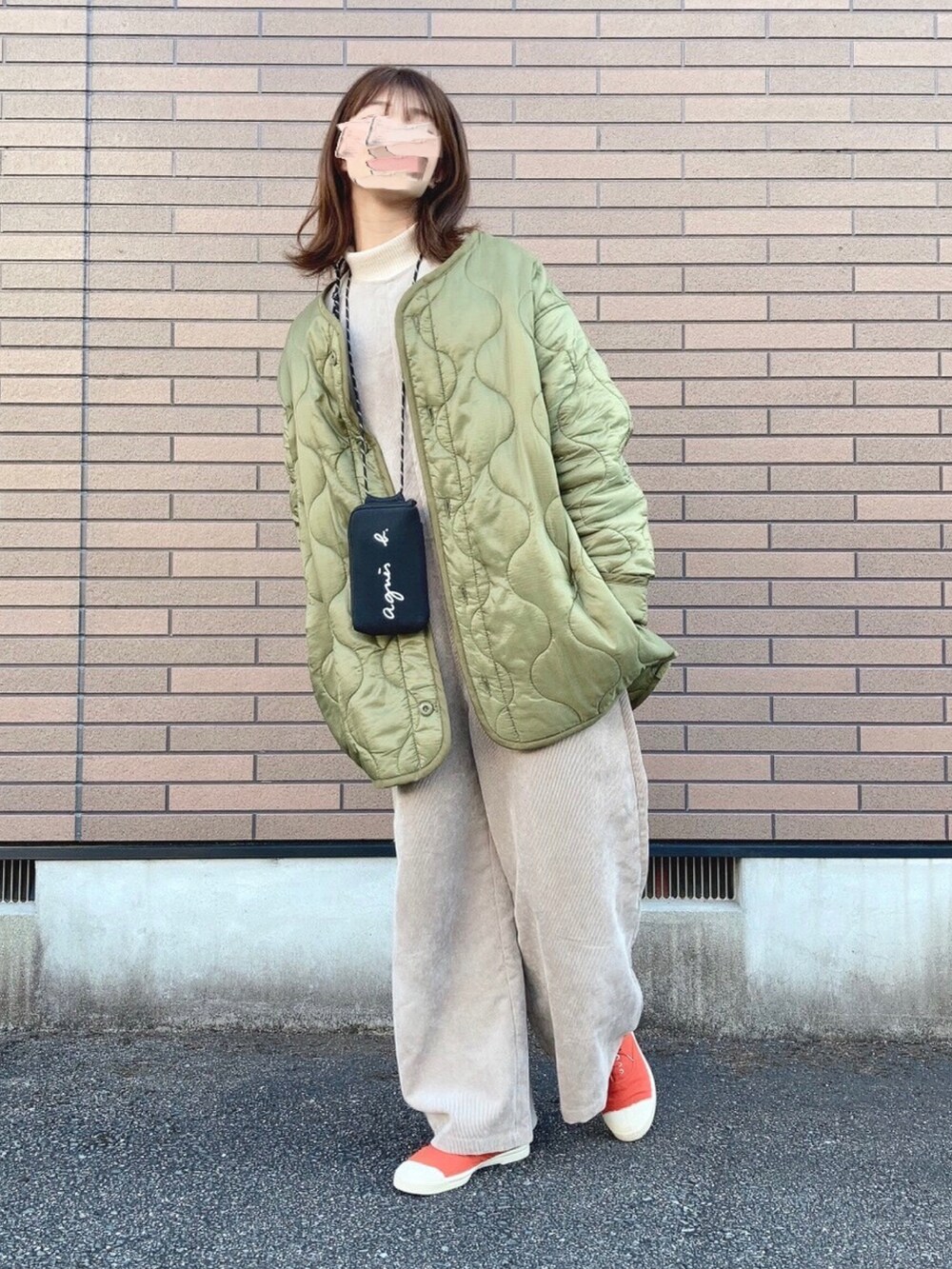 グリーン系のジャケット/アウター、ベージュ系のサロペット/オーバーオール、オレンジ系のスニーカーを着用したレディースの冬コーディネートの3枚目の写真