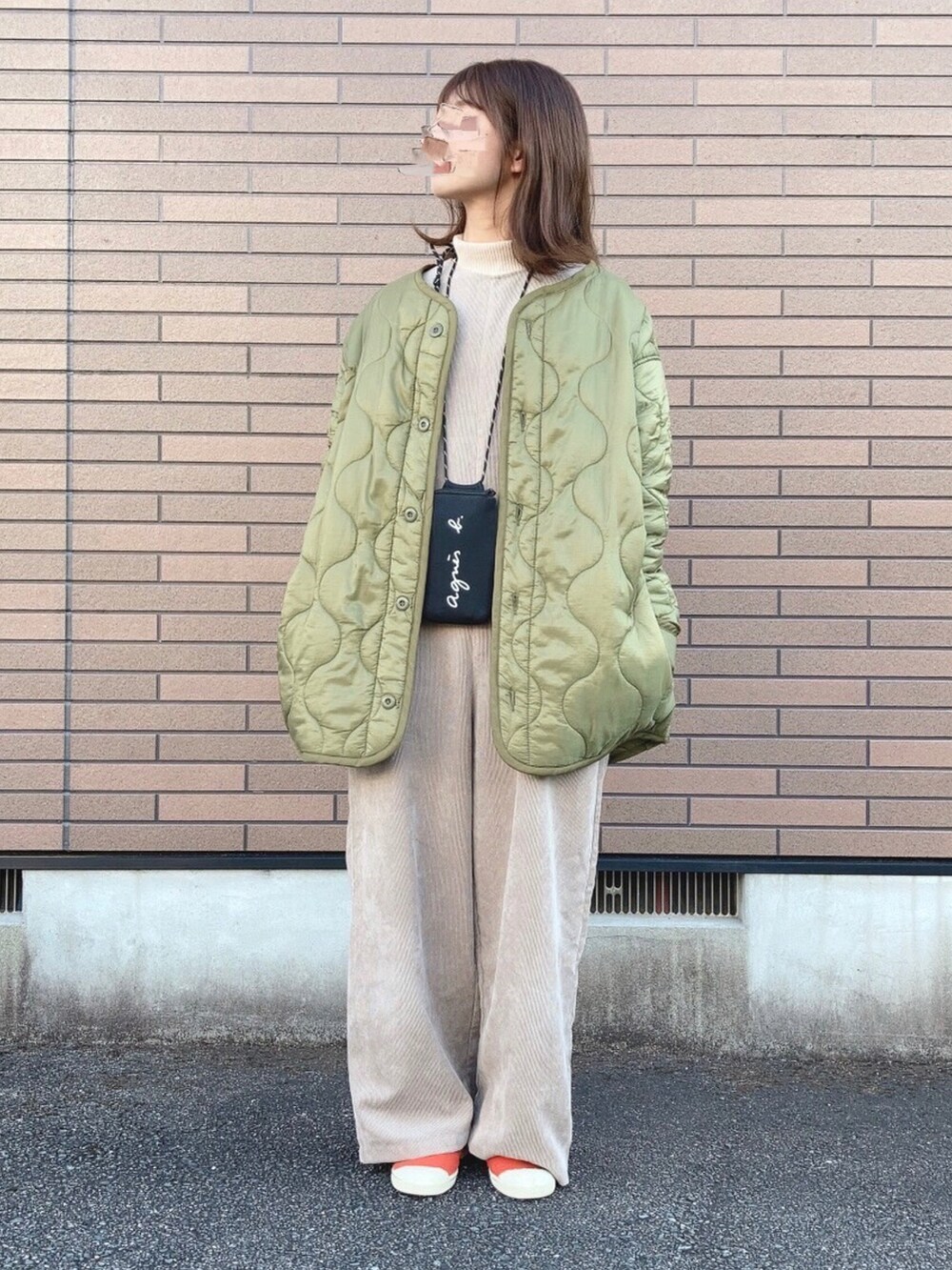 グリーン系のジャケット/アウター、ベージュ系のサロペット/オーバーオール、オレンジ系のスニーカーを着用したレディースの冬コーディネートの2枚目の写真