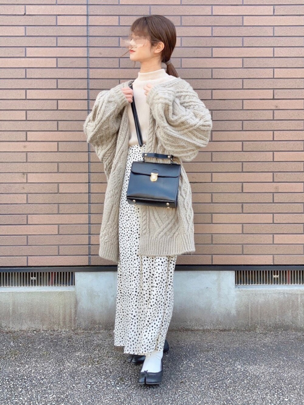 ベージュ系のカーディガン/ボレロ、ブラック系のショルダーバッグ、ホワイト系のニット/セーターを着用したレディースの冬コーディネートの2枚目の写真