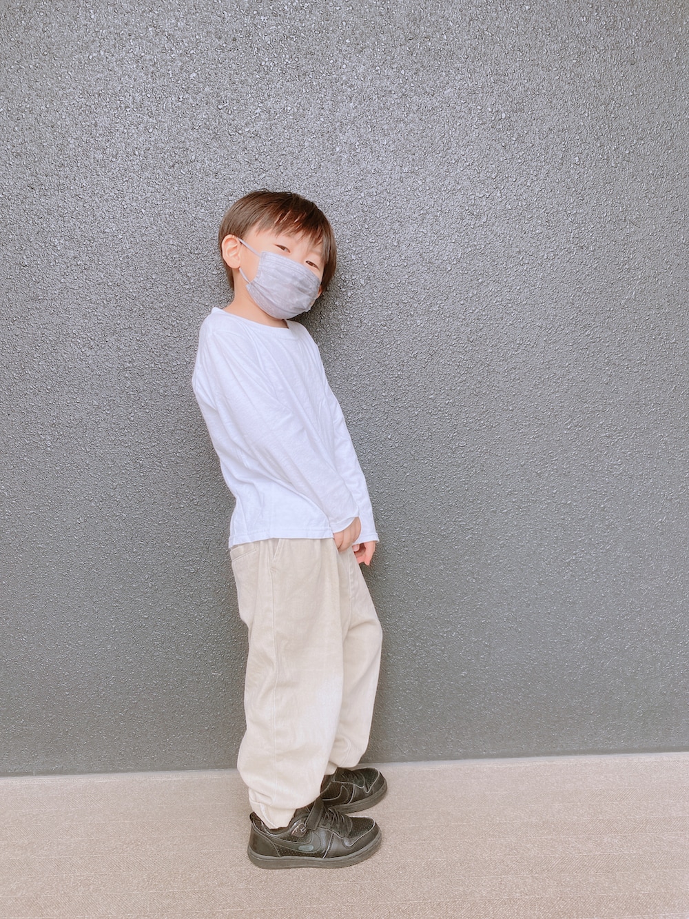 ベージュ系のチノパンツ、ブラック系のスニーカー、グリーン系のキャップを着用したキッズの秋コーディネートの2枚目の写真