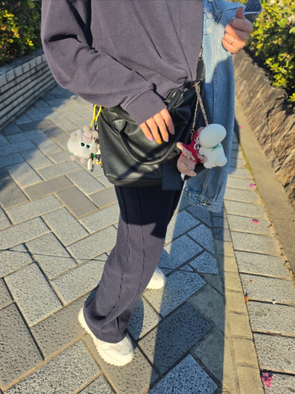 ホワイト系のスニーカー、ホワイト系のスニーカー、ブラック系のデニムパンツを着用したレディースの春コーディネートの2枚目の写真