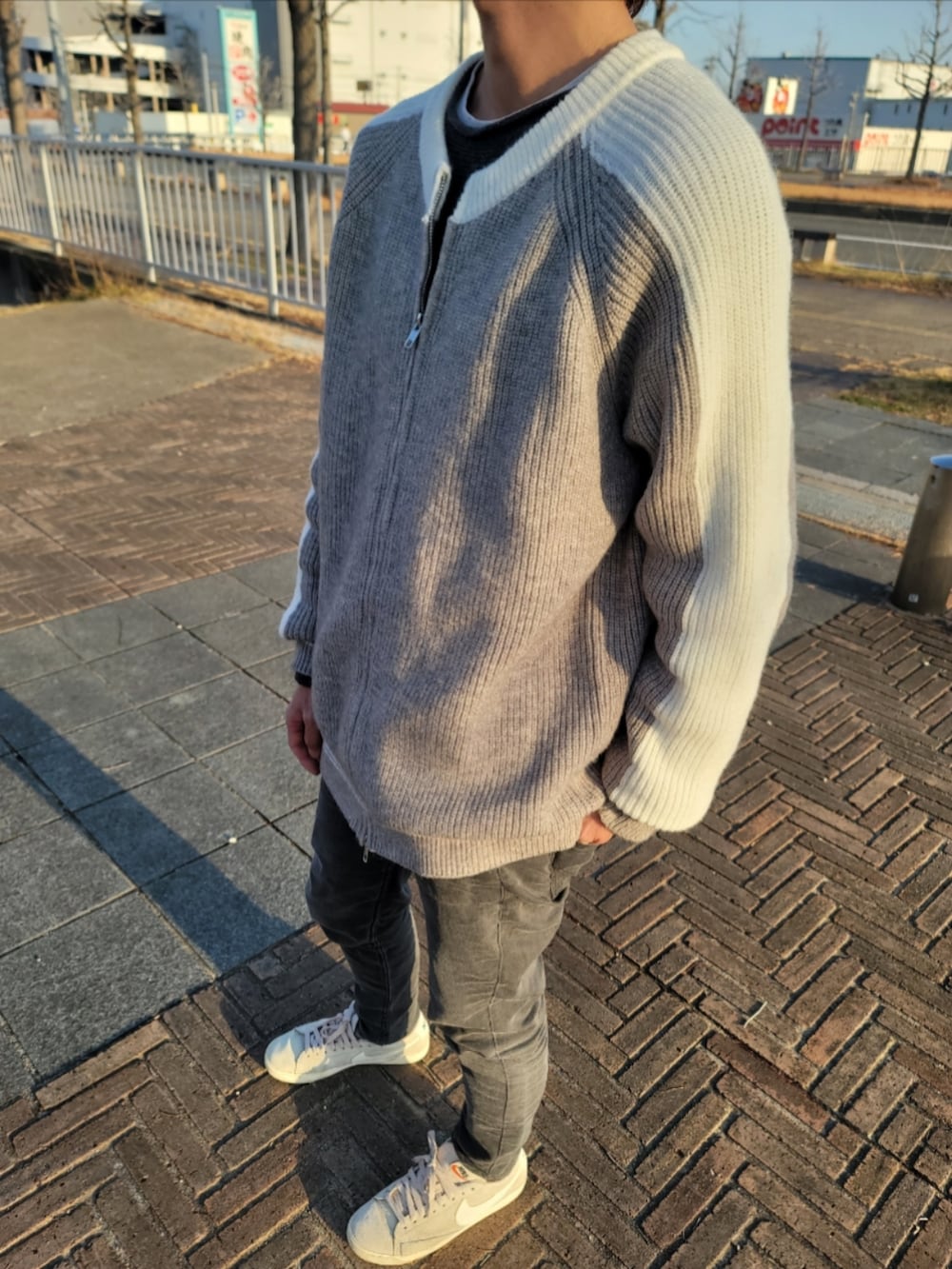 グレー系のニット/セーター、グレー系のドラムバッグ、ブラック系のブーティを着用したレディースの春コーディネートの3枚目の写真