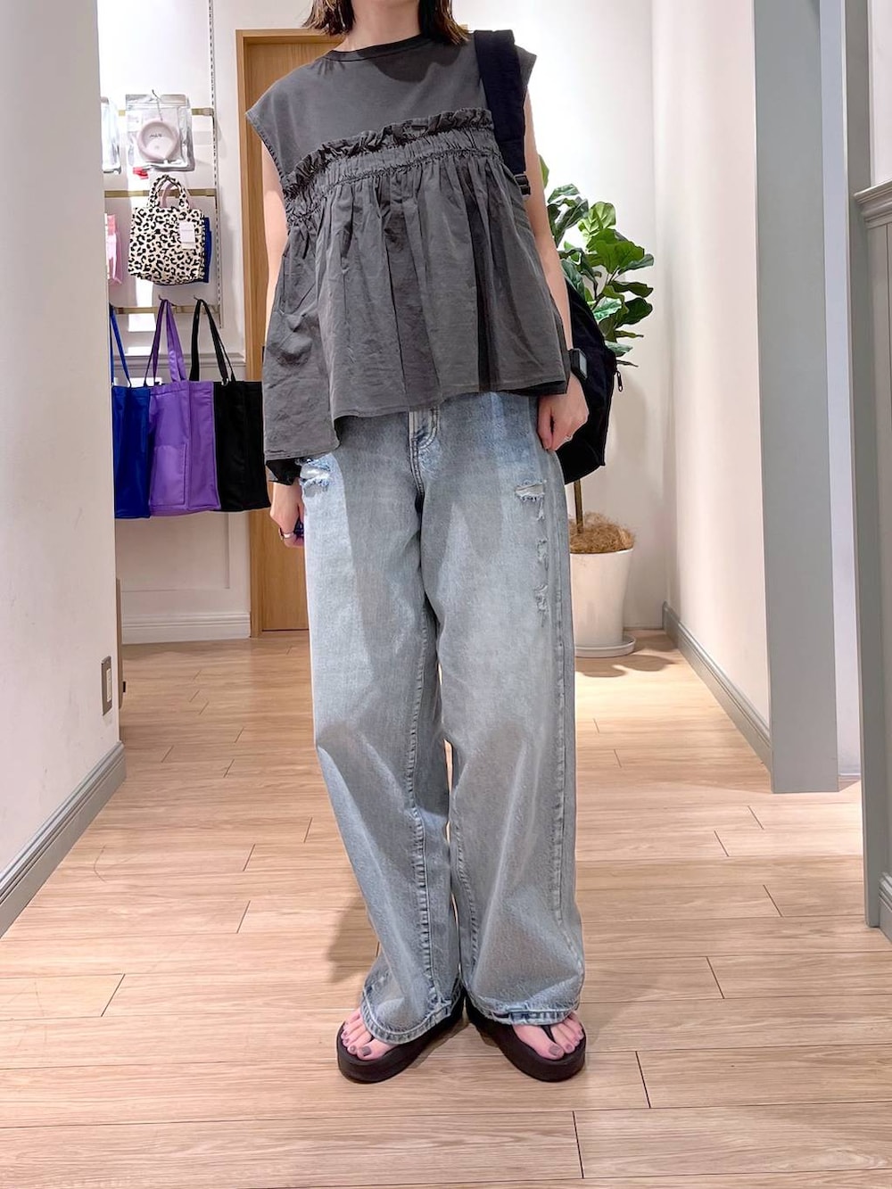 ブラック系のショルダーバッグ、ブルー系のデニムパンツ、グレー系のTシャツ/カットソーを着用したレディースの夏コーディネートの2枚目の写真
