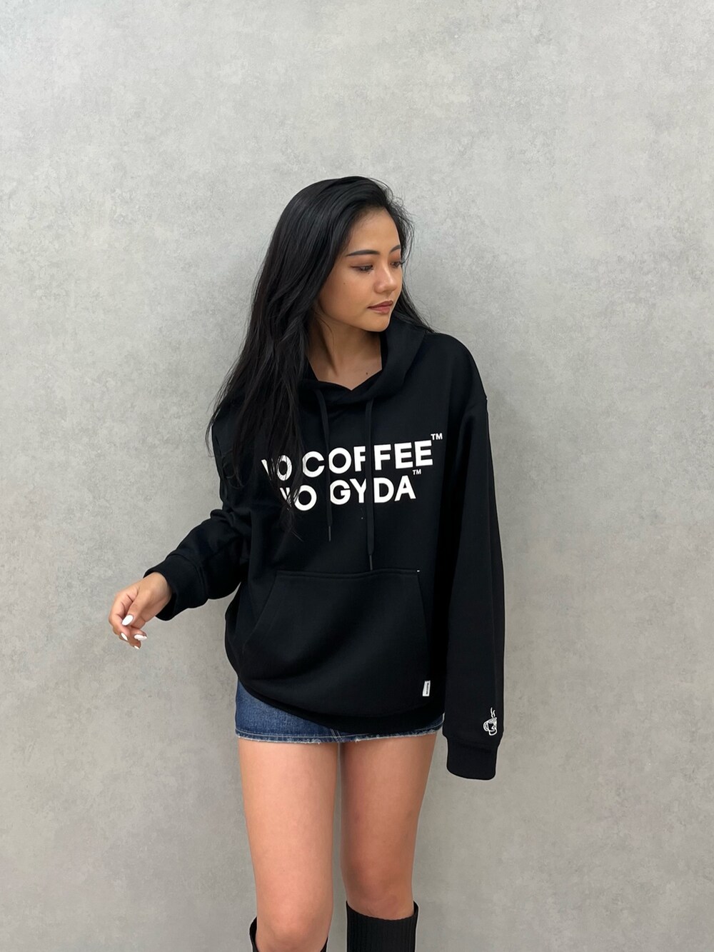 ブラック系のパーカー、ブラック系のブーツ、ブルー系のデニムスカートを着用したレディースの秋コーディネートの2枚目の写真