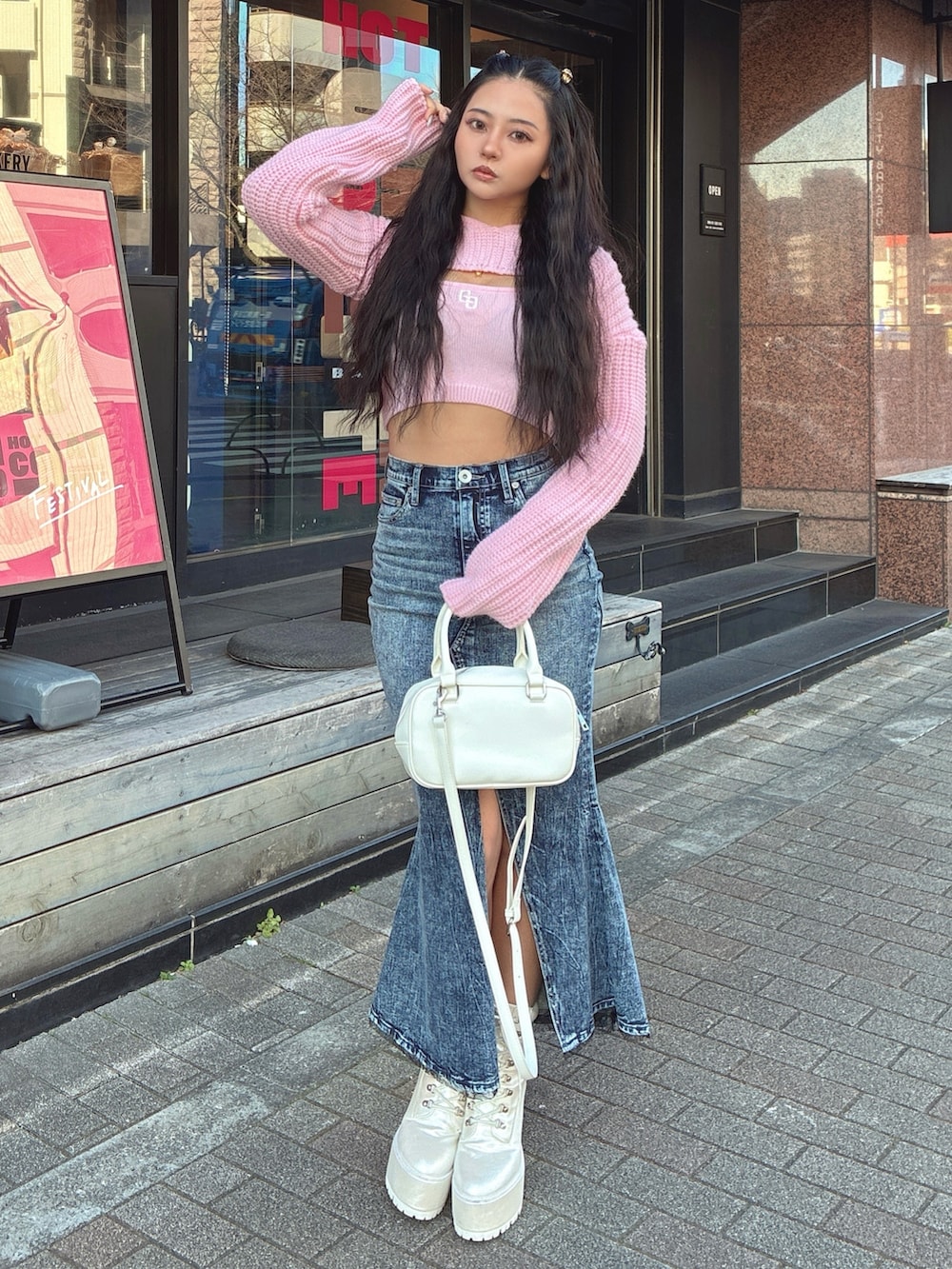 ピンク系のニット/セーター、ブルー系のデニムスカート、ホワイト系のブーツを着用したレディースの冬コーディネートの2枚目の写真