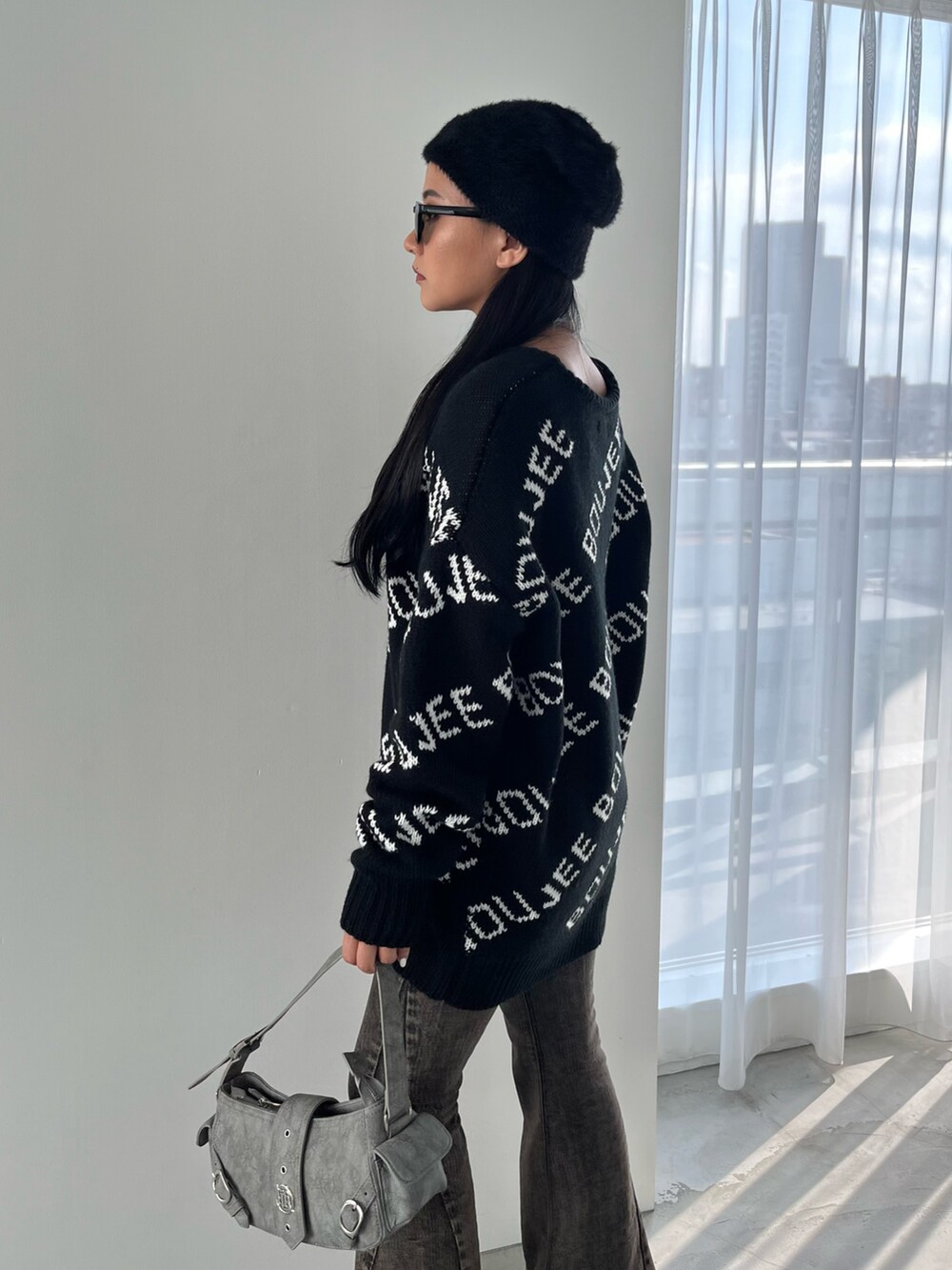 グリーン系のショルダーバッグ、ブラック系のブーツ、ブラック系のデニムパンツを着用したレディースの秋コーディネートの2枚目の写真