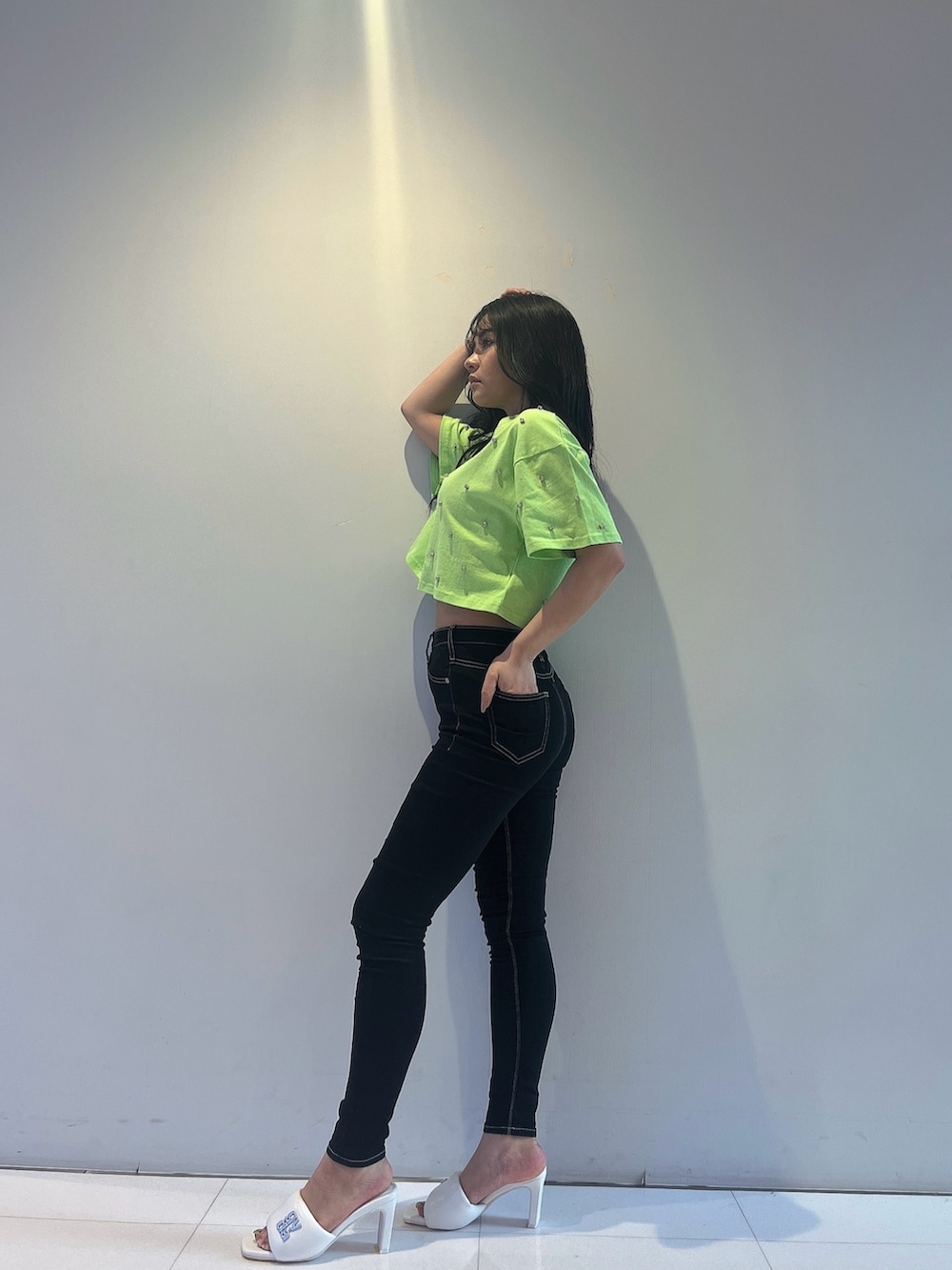 グリーン系のTシャツ/カットソー、ブラック系のデニムパンツ、ホワイト系のサンダルを着用したレディースの春コーディネートの2枚目の写真