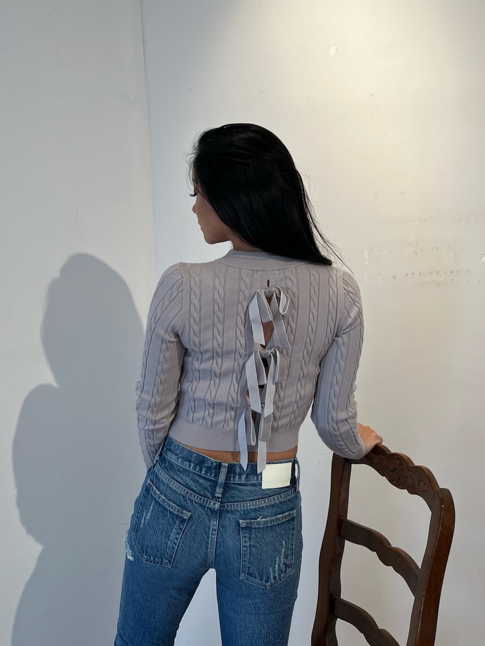 グレー系のニット/セーター、ブルー系のデニムパンツ、ホワイト系のブーツを着用したレディースの秋コーディネートの3枚目の写真