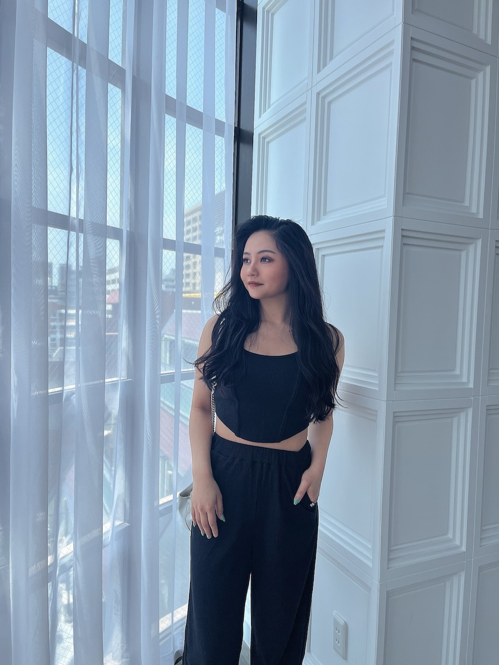 ブラック系のキャミソール、ブラック系のスウェットパンツ、ホワイト系のパンプスを着用したレディースの夏コーディネートの3枚目の写真