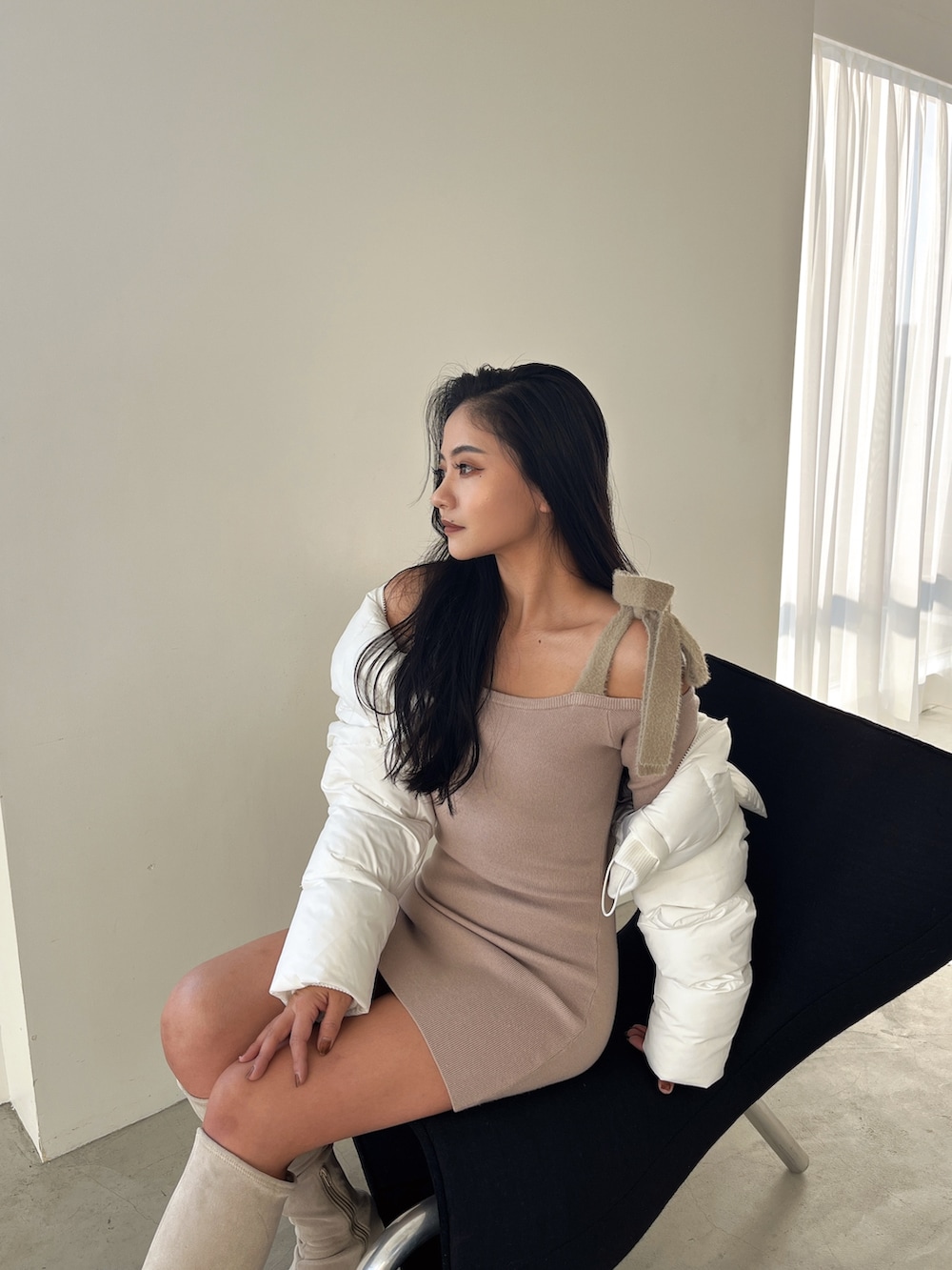 ベージュ系のワンピース、ホワイト系のダウンジャケット/コート、ホワイト系のブーツを着用したレディースの冬コーディネートの2枚目の写真